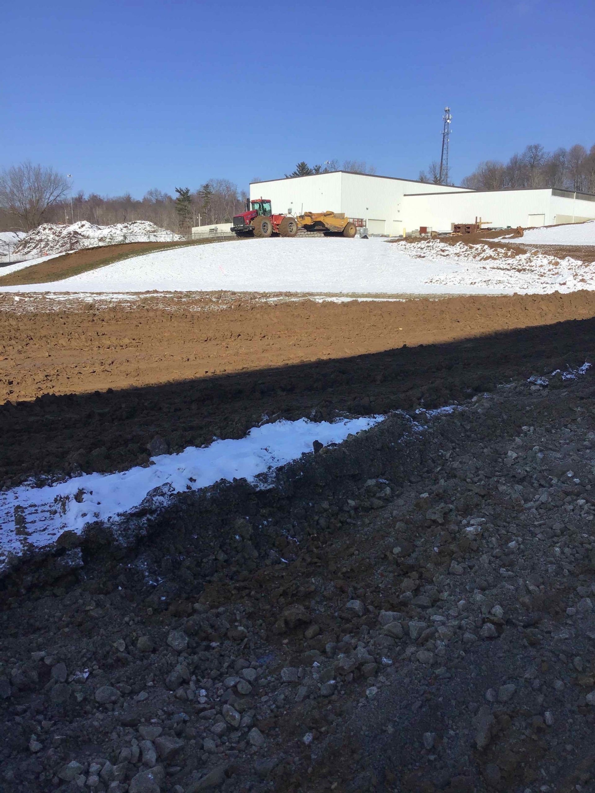 A large puddle of water is in the middle of a dirt field.