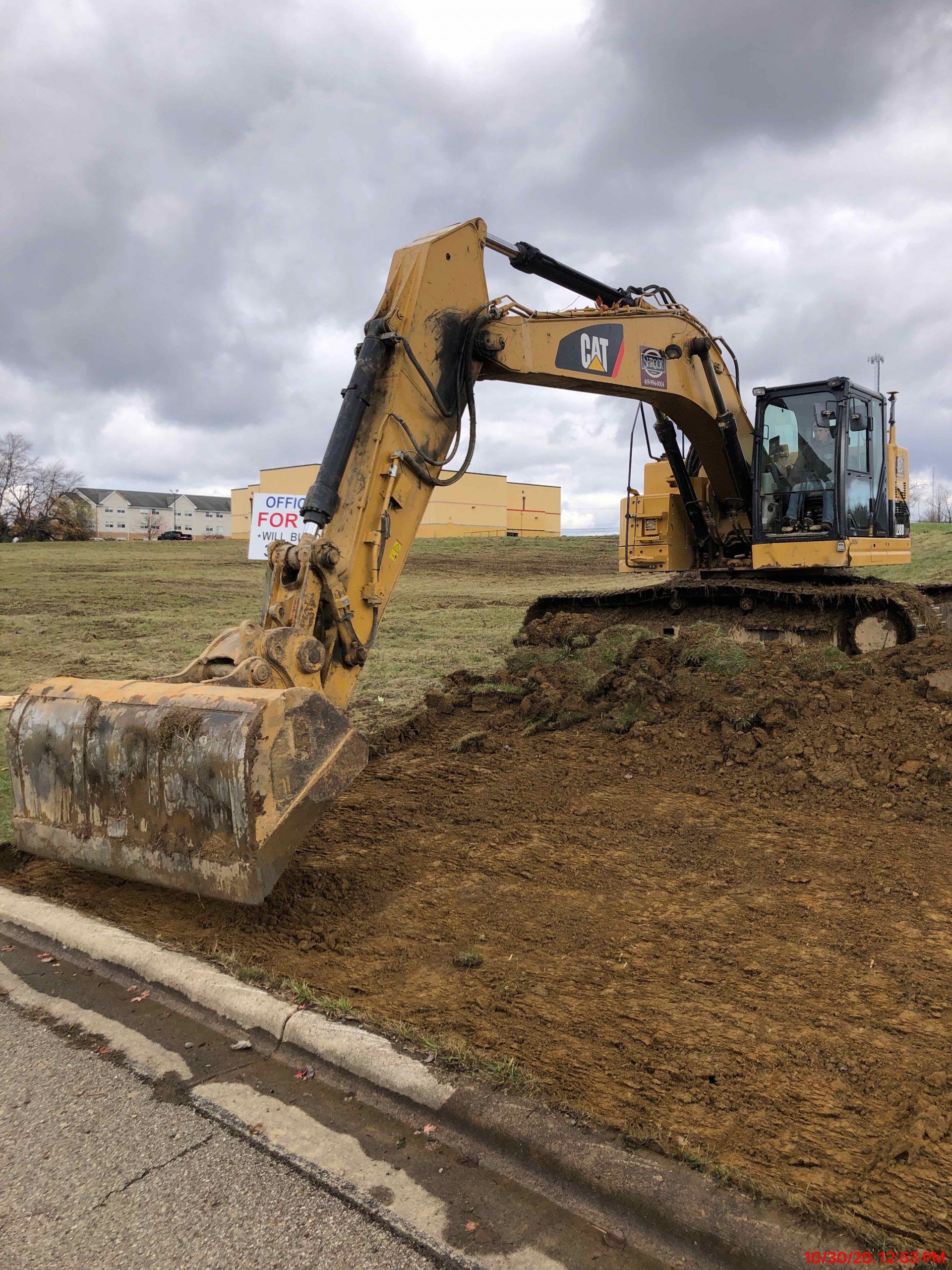 A large excavator is sitting on top of a pile of dirt in a field.