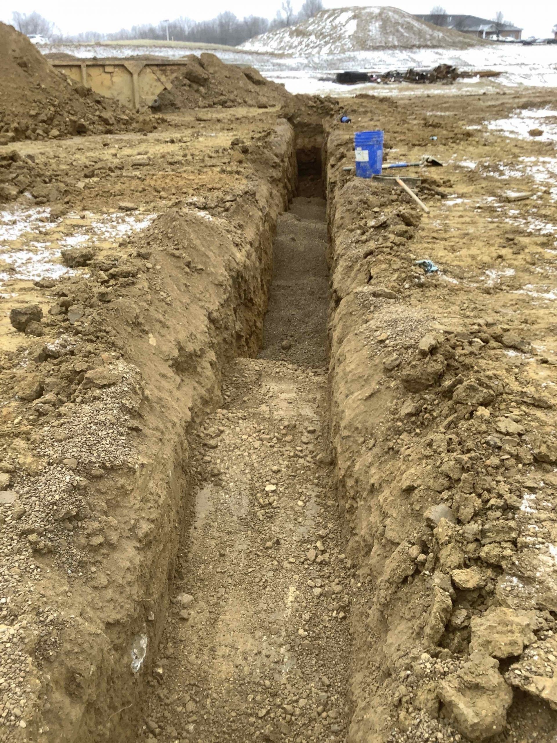 A trench is being dug in the dirt in a field.