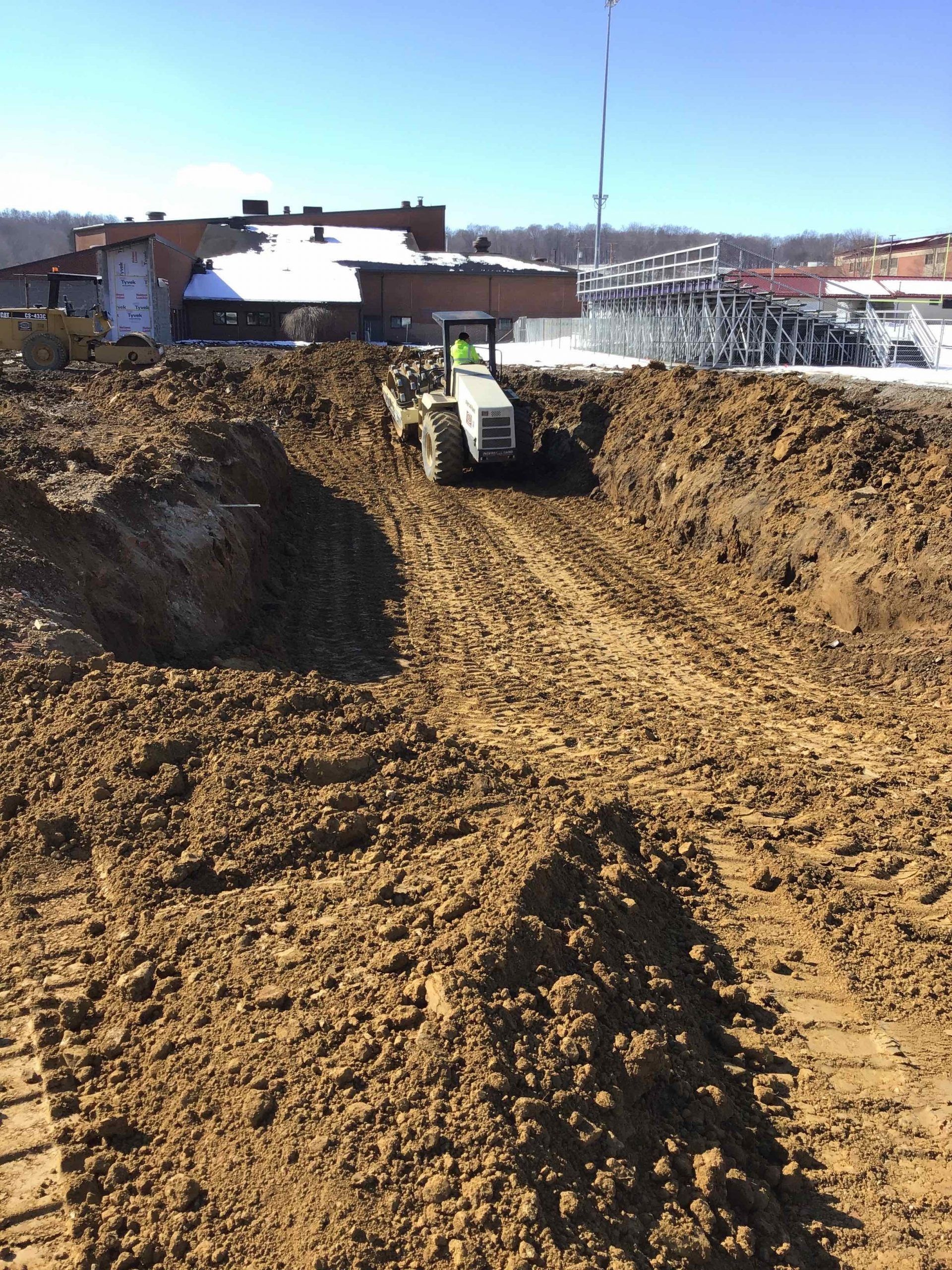 A tractor is driving through a dirt field.