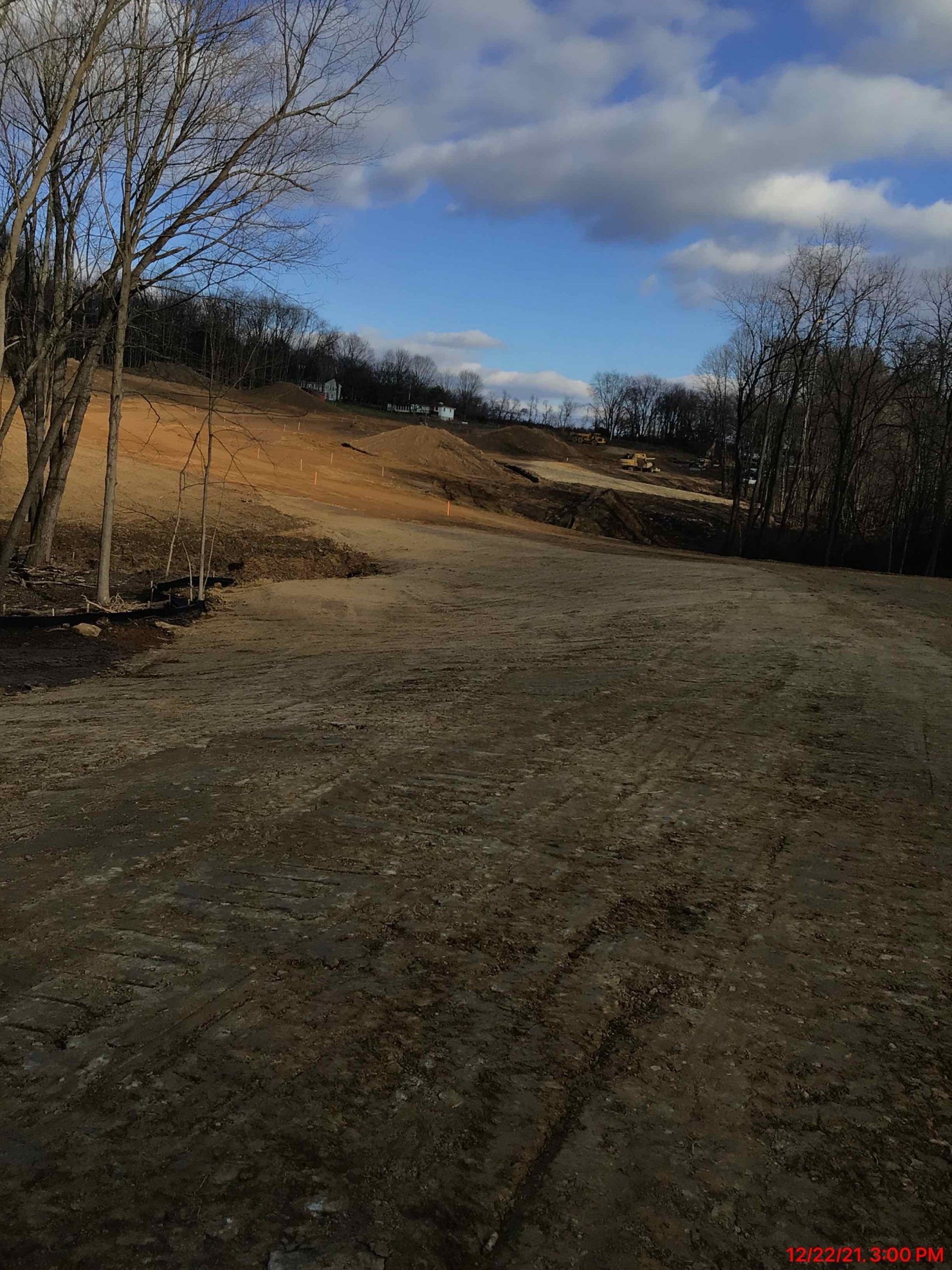 A dirt field with trees and a blue sky in the background.
