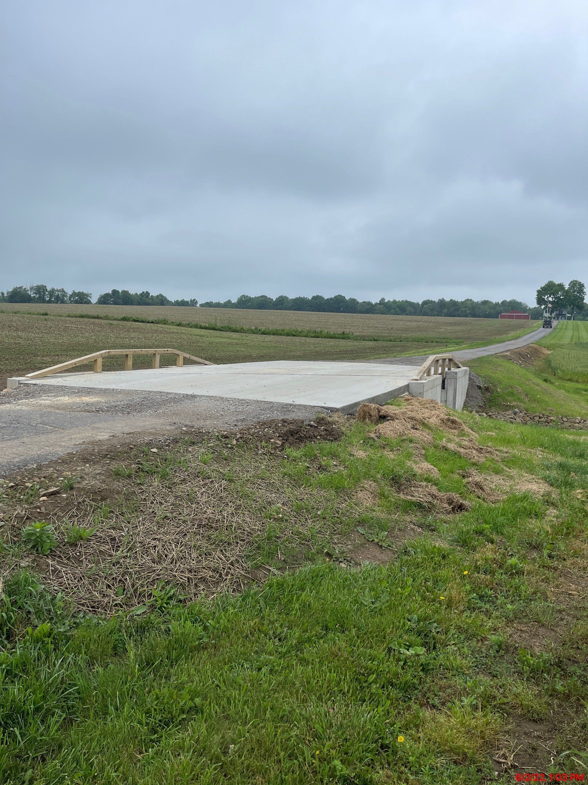 A dirt road going through a grassy field on a cloudy day.
