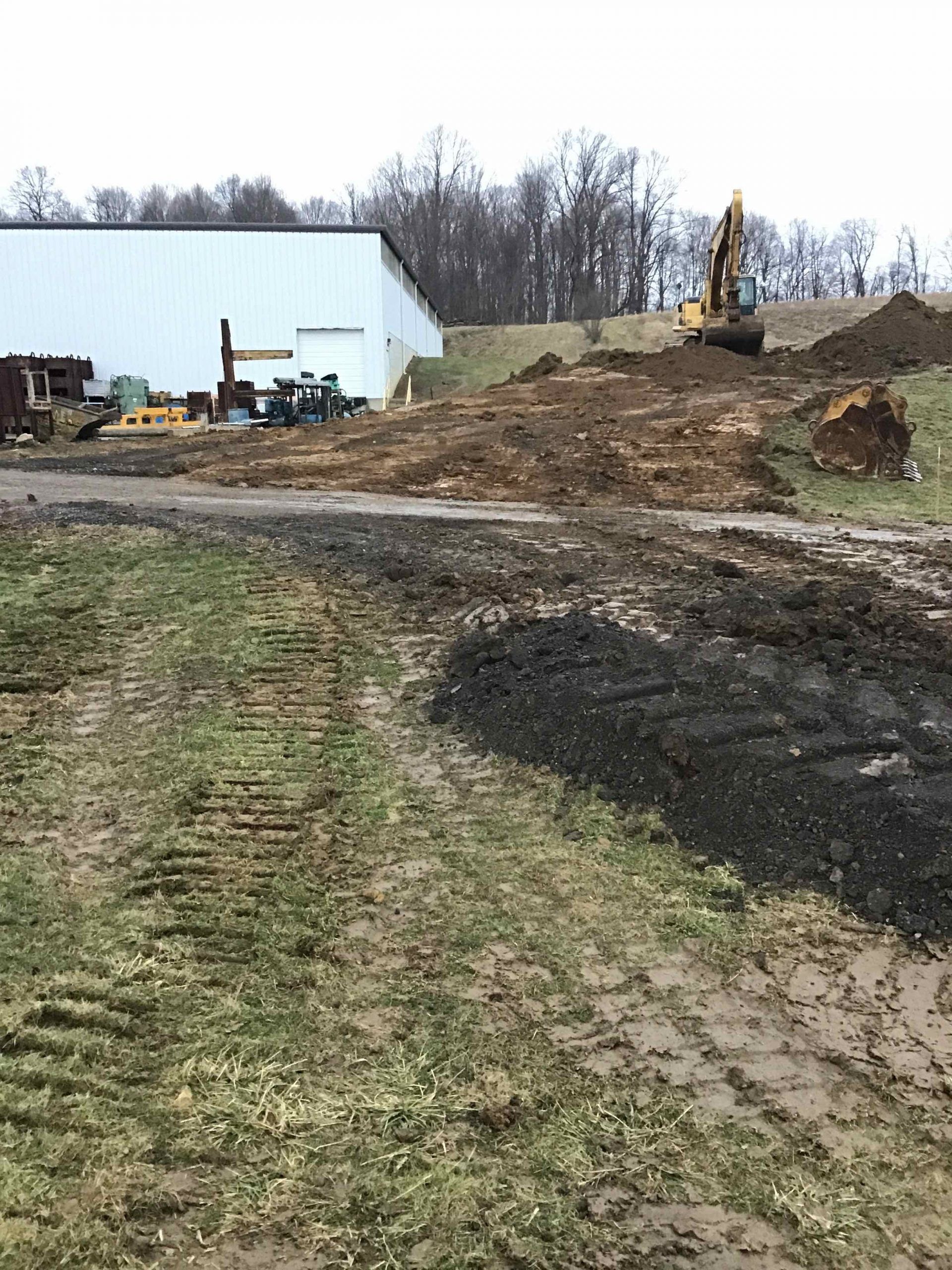 A large pile of dirt is sitting on the side of a dirt road.
