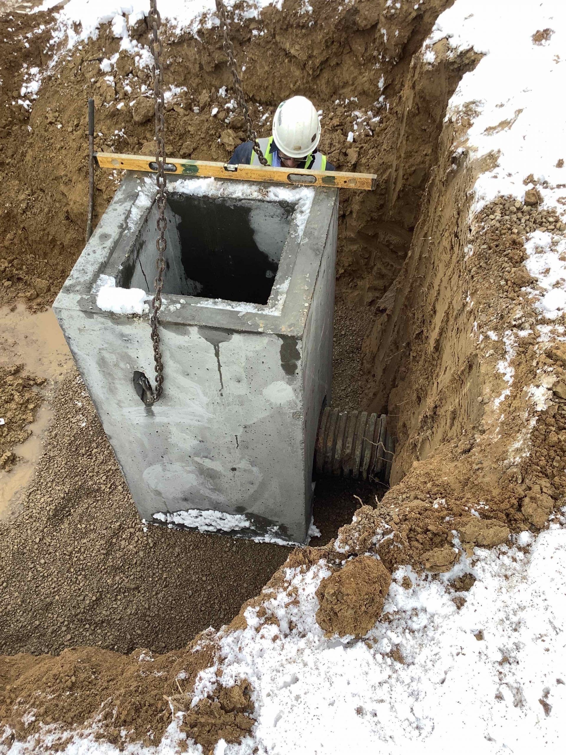 A man is standing in the dirt next to a concrete box.