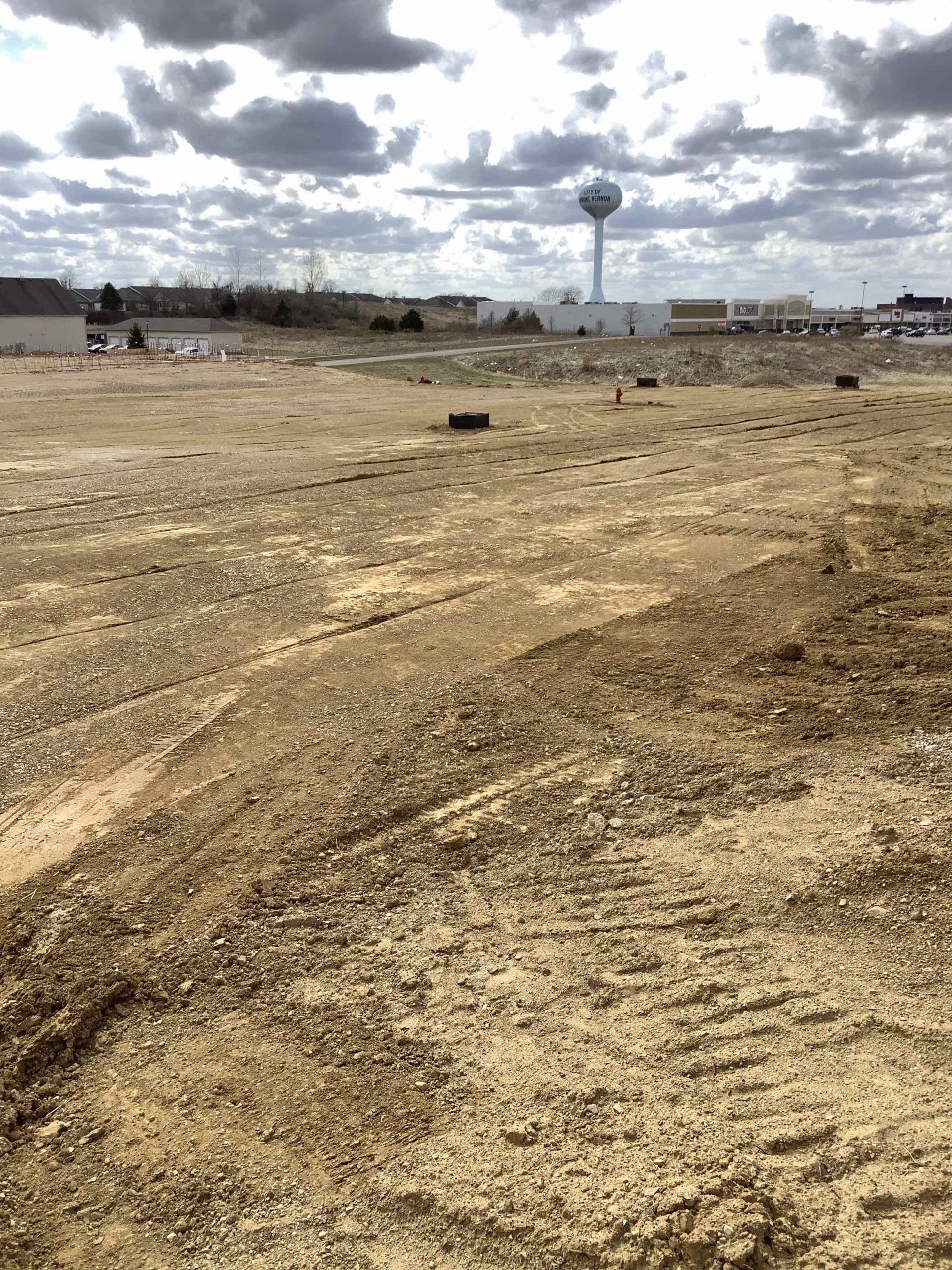 A large dirt field with a water tower in the background.