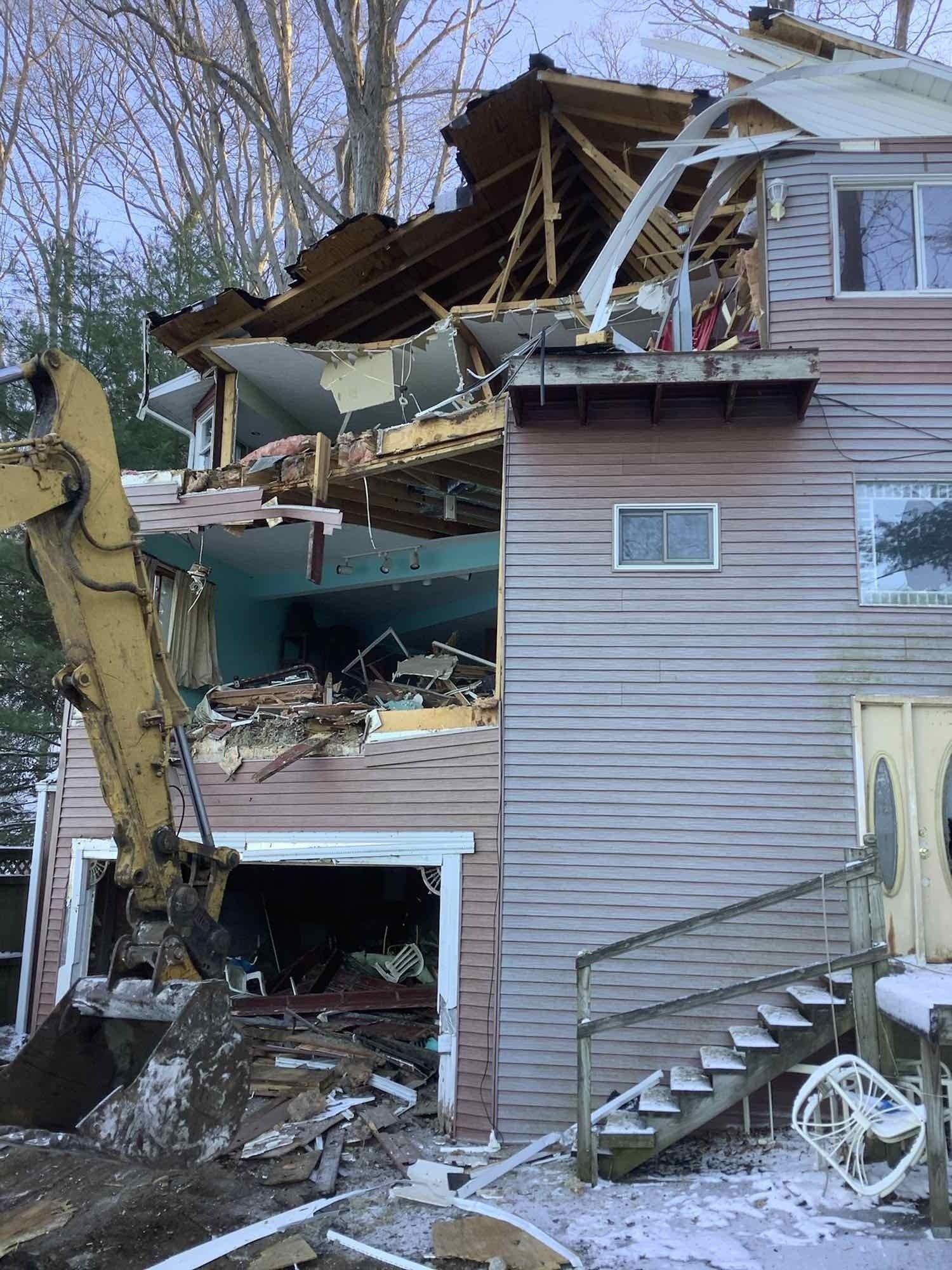 A house is being demolished by a bulldozer.