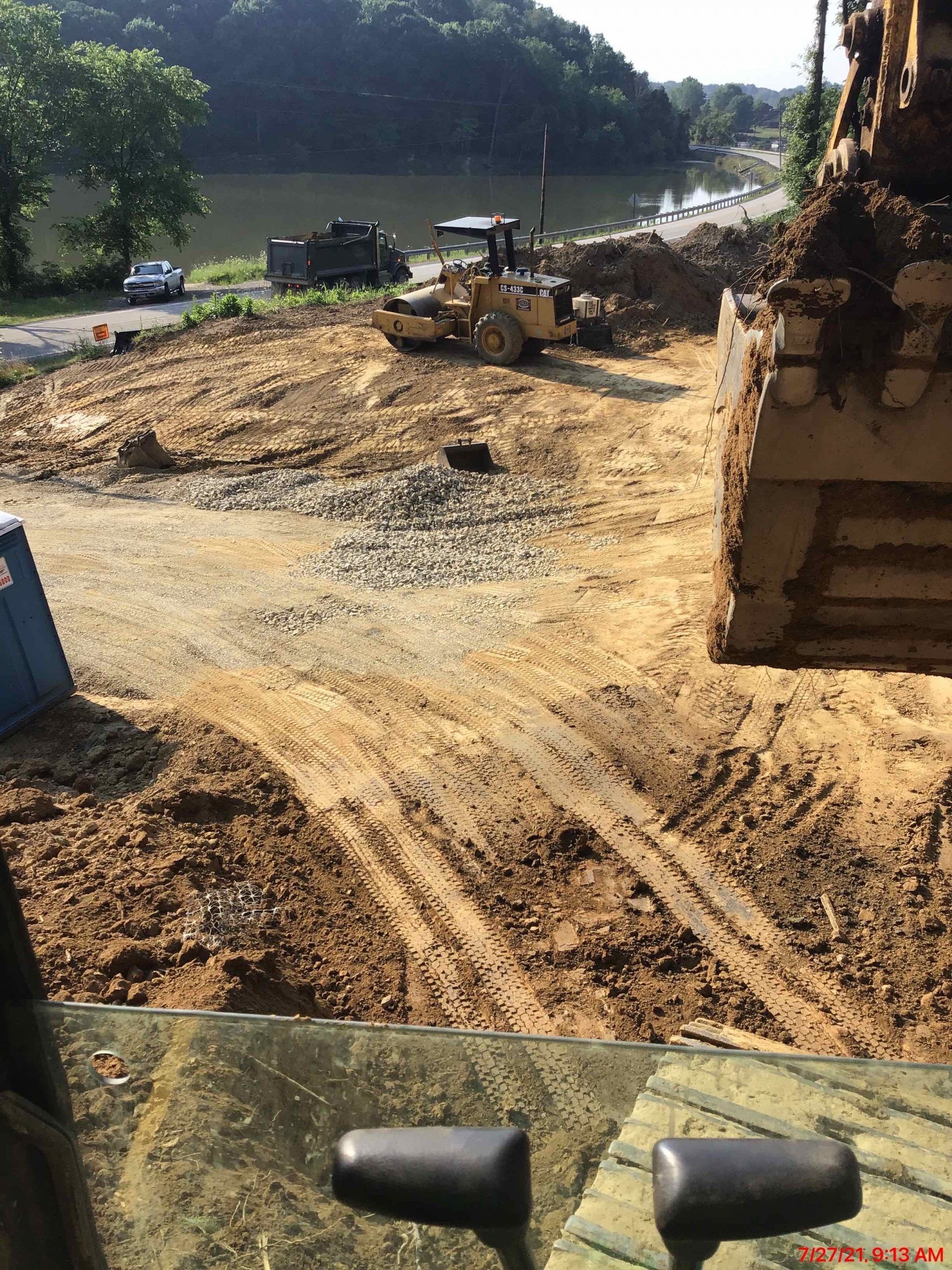 A bulldozer is moving dirt on a construction site next to a body of water.