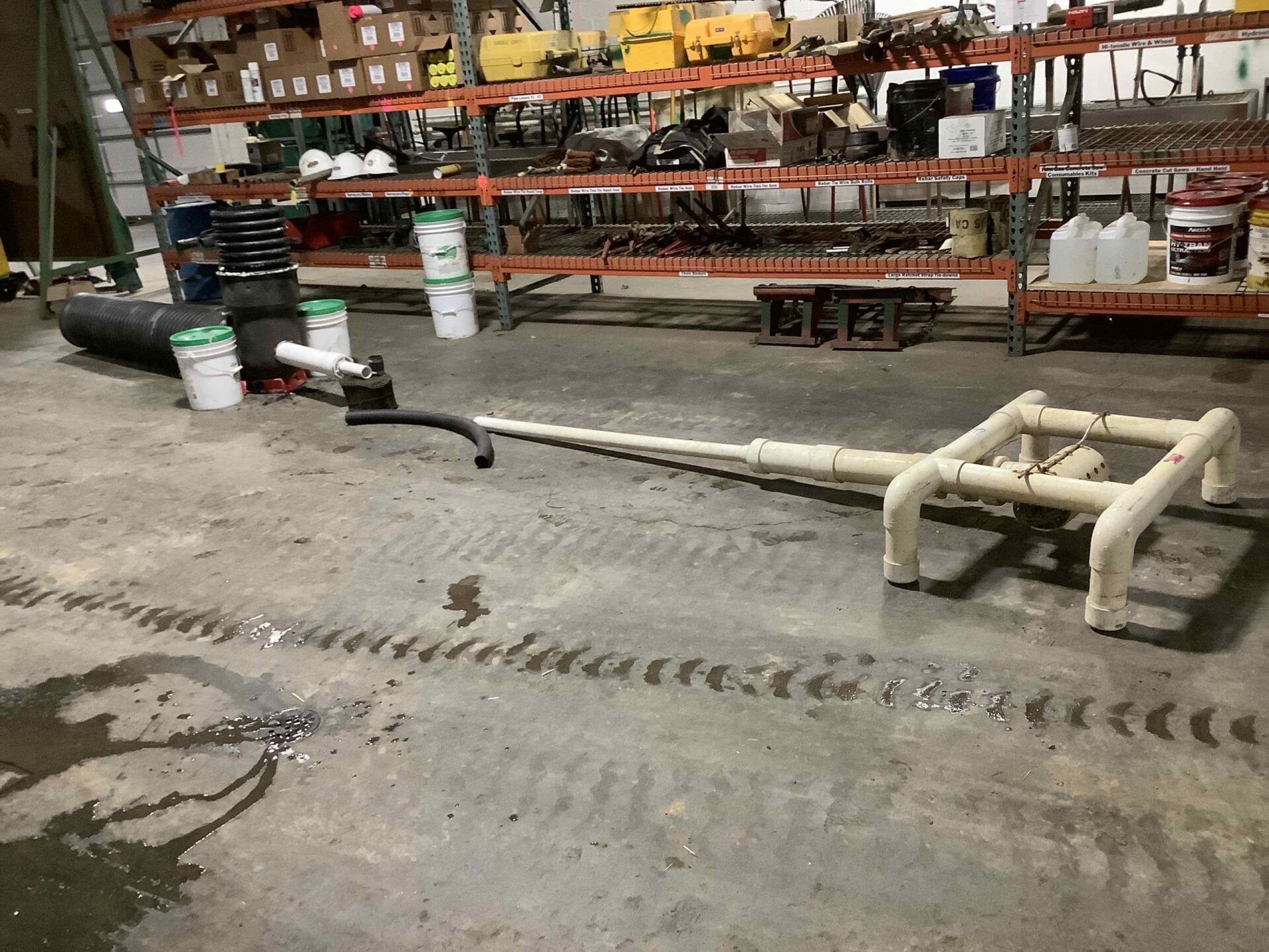 A warehouse with a lot of shelves and pipes on the floor.