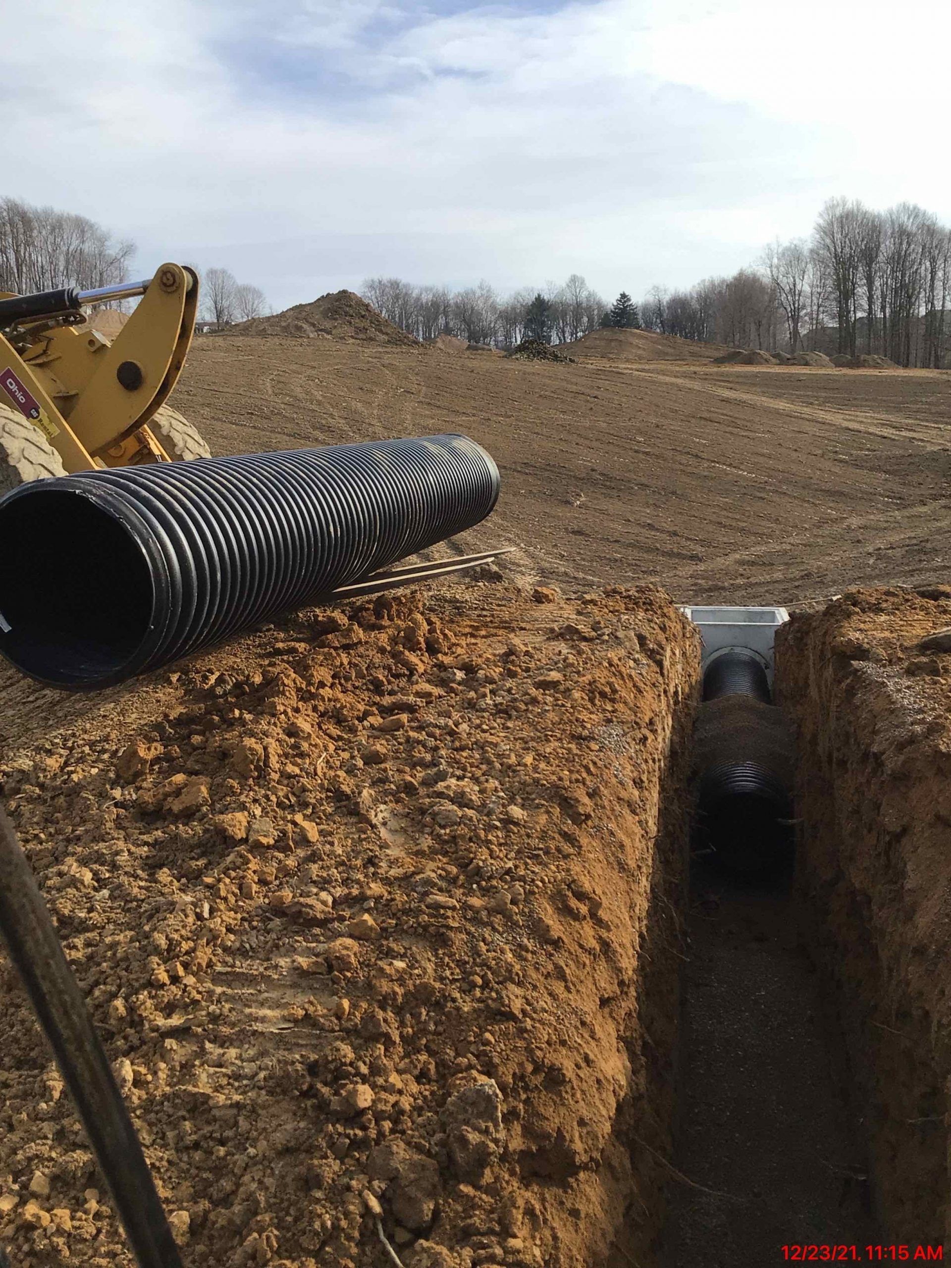 A large pipe is sitting in the middle of a dirt field.