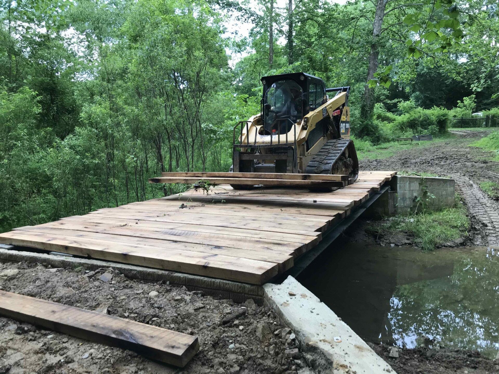A bulldozer is sitting on top of a wooden platform over a body of water.