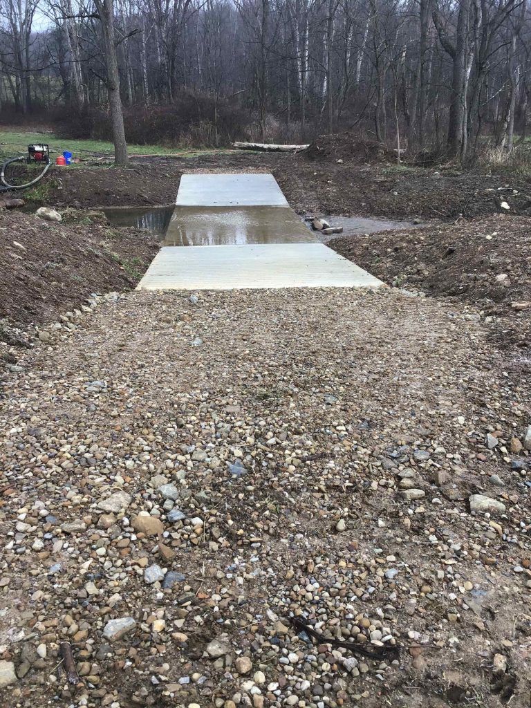A concrete walkway is being built over a stream.