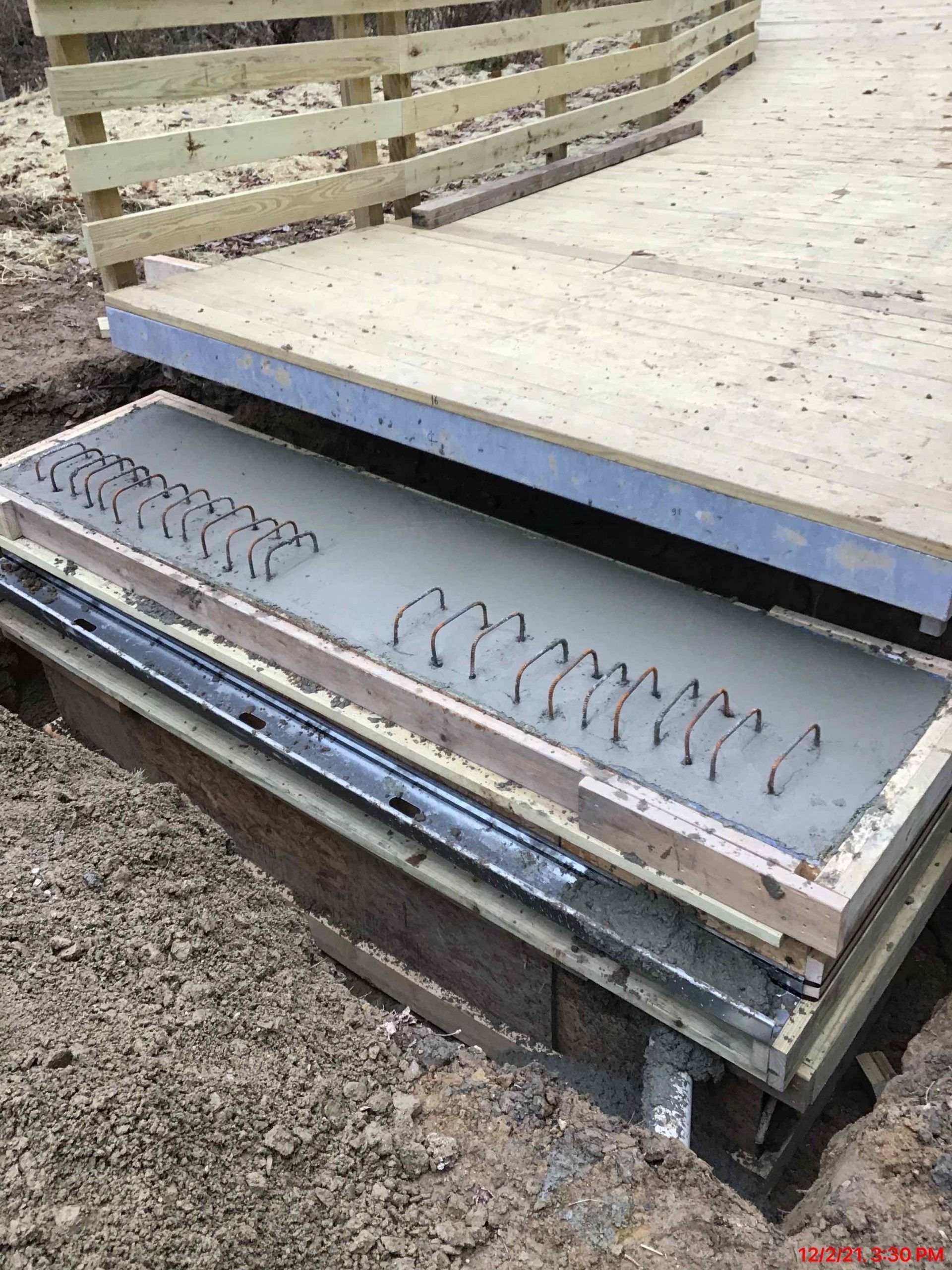 A wooden box filled with concrete is sitting on top of a pile of gravel.