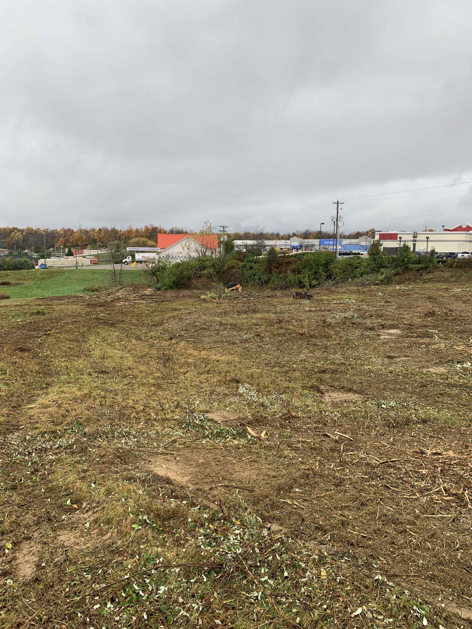 A large field with buildings in the background and a cloudy sky.