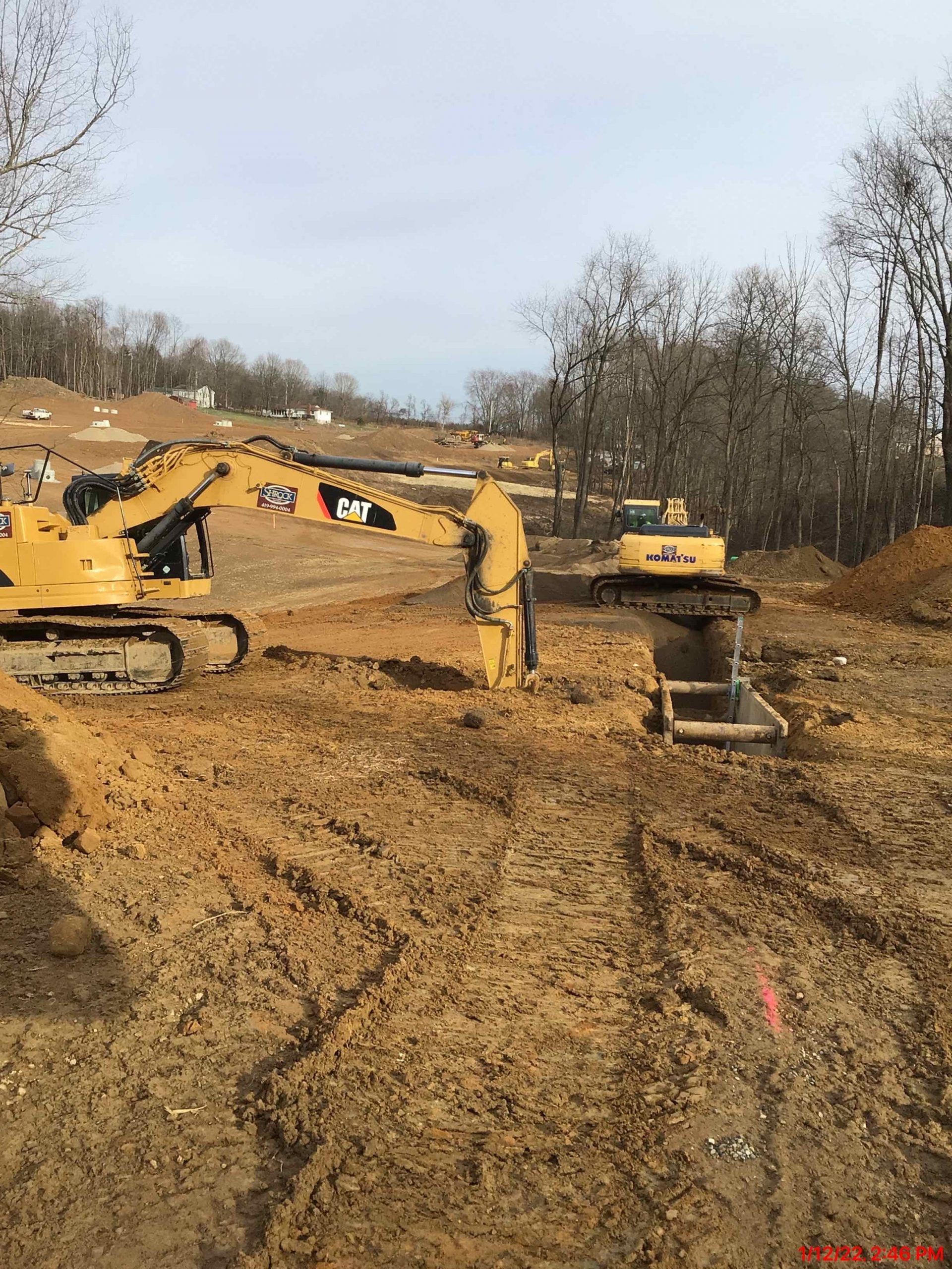 A construction site with a lot of dirt and trees in the background.