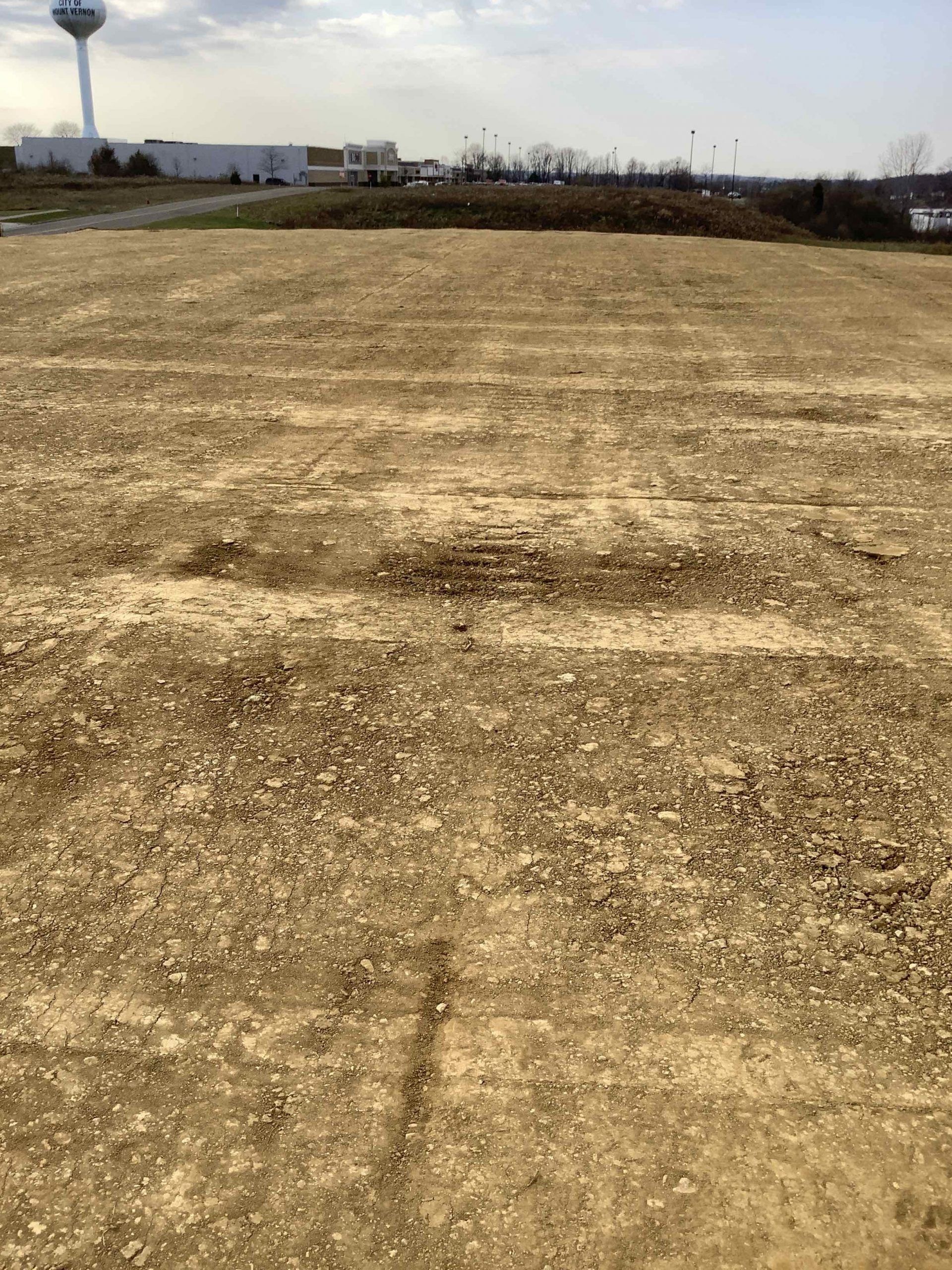 A large dirt field with a water tower in the background.
