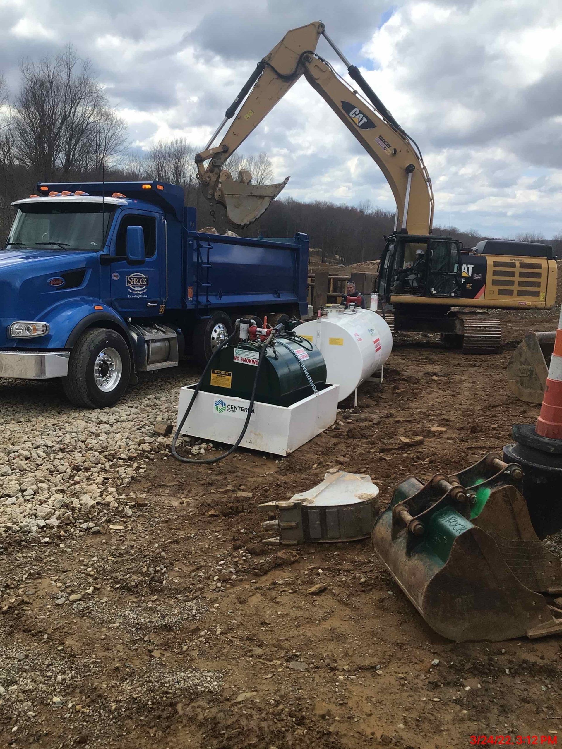 A dump truck and an excavator are parked in a dirt field.
