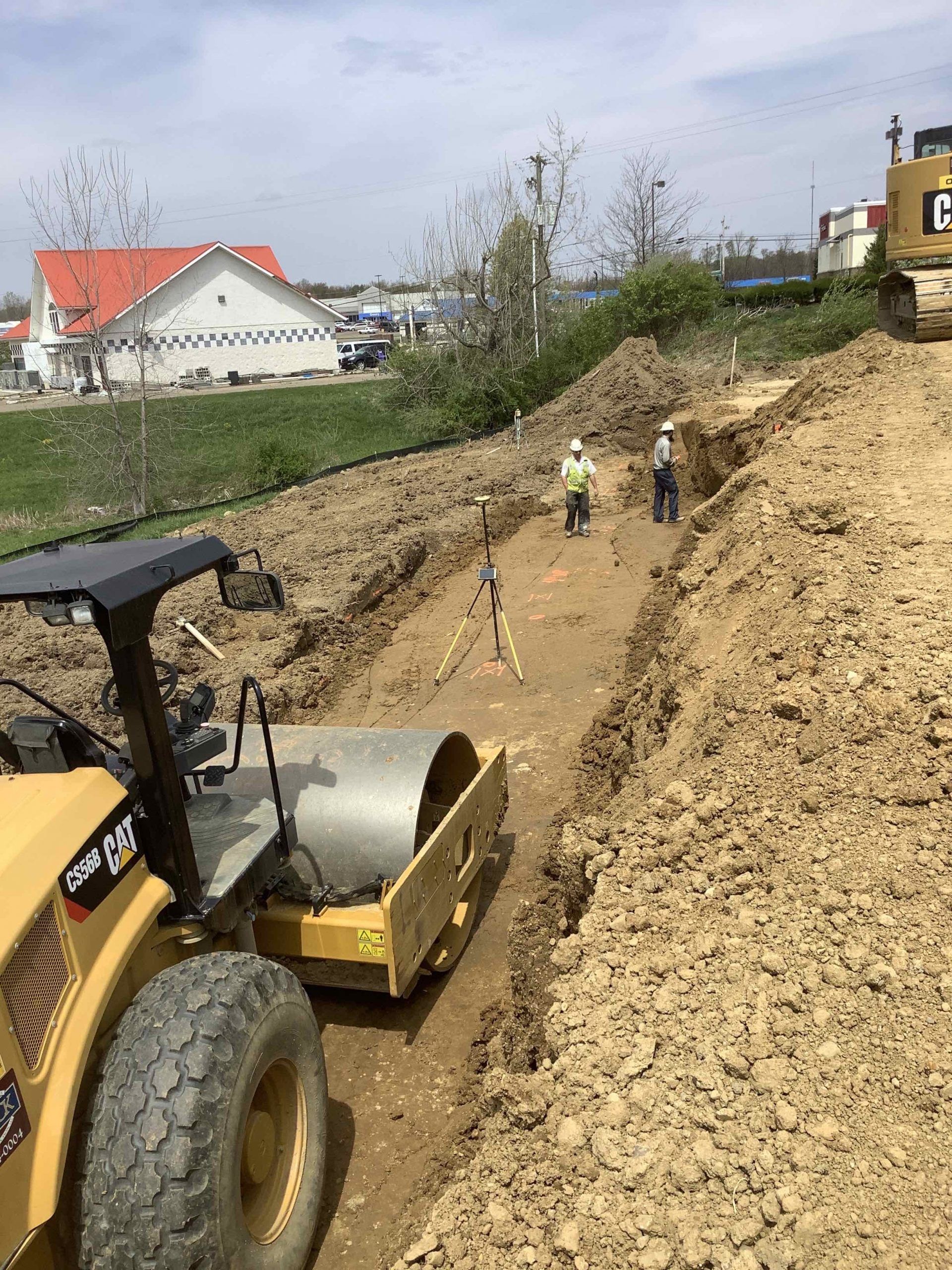 A construction site with a tractor and a roller in the dirt.