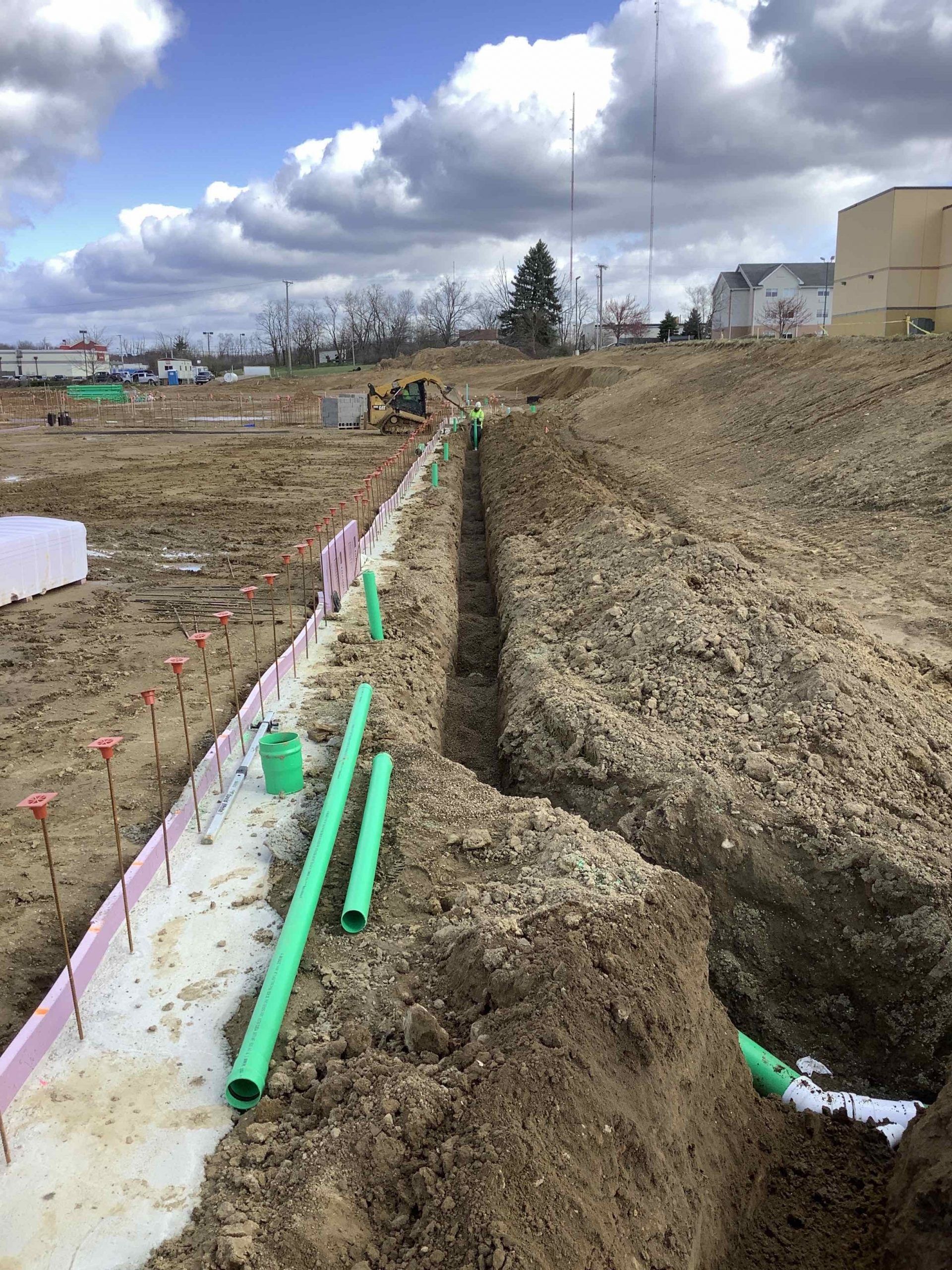 A construction site with green pipes in the dirt.