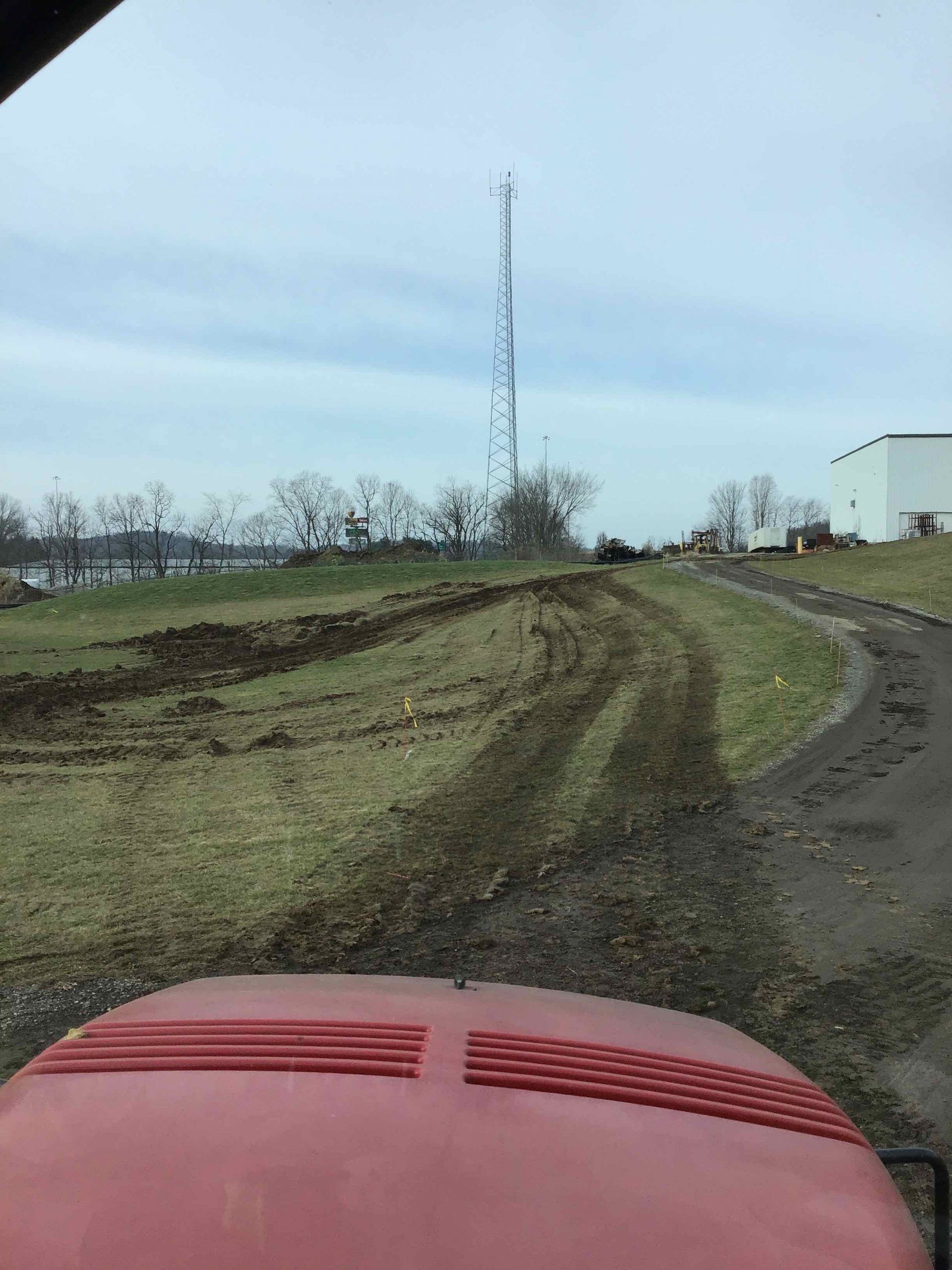 A red tractor is driving down a dirt road.