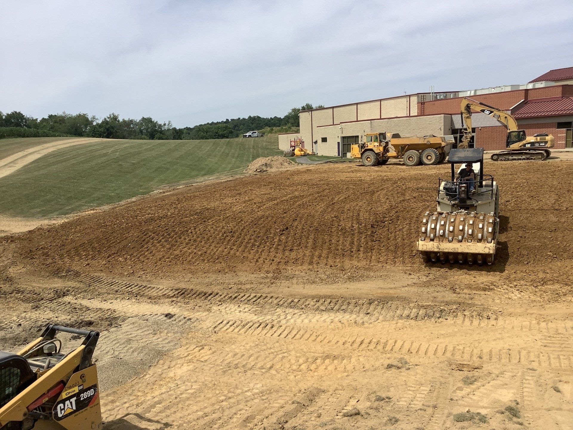 A bulldozer is moving dirt on a construction site in front of a building.