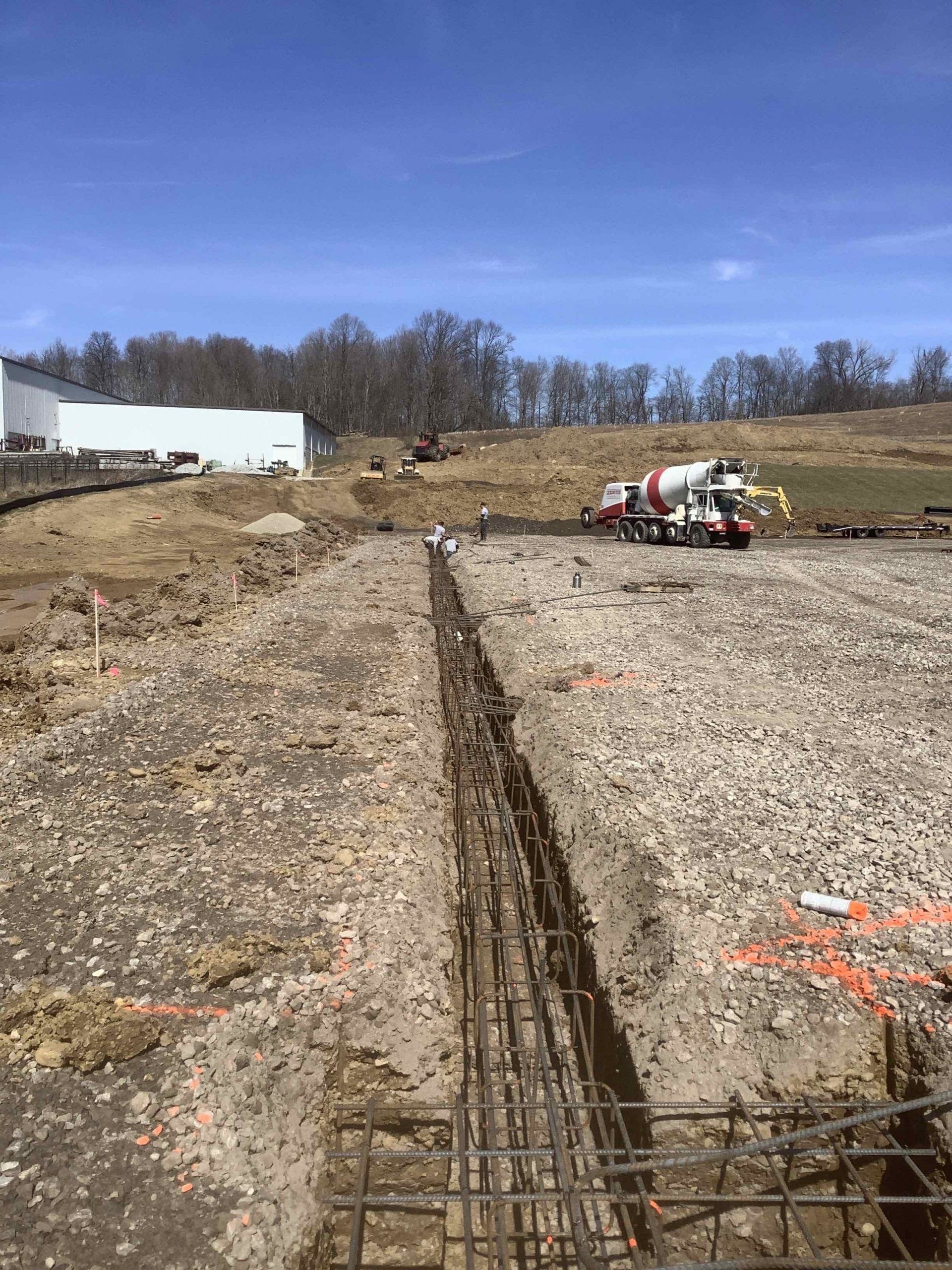 A concrete mixer truck is driving down a dirt road.