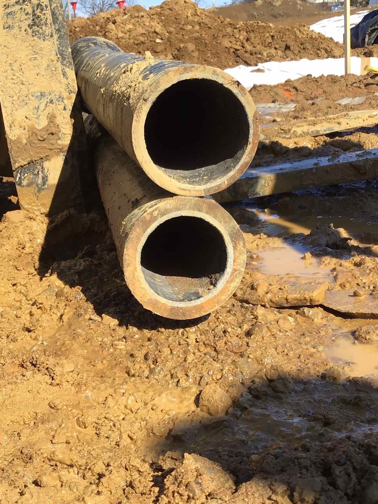 Two pipes are stacked on top of each other in the dirt.