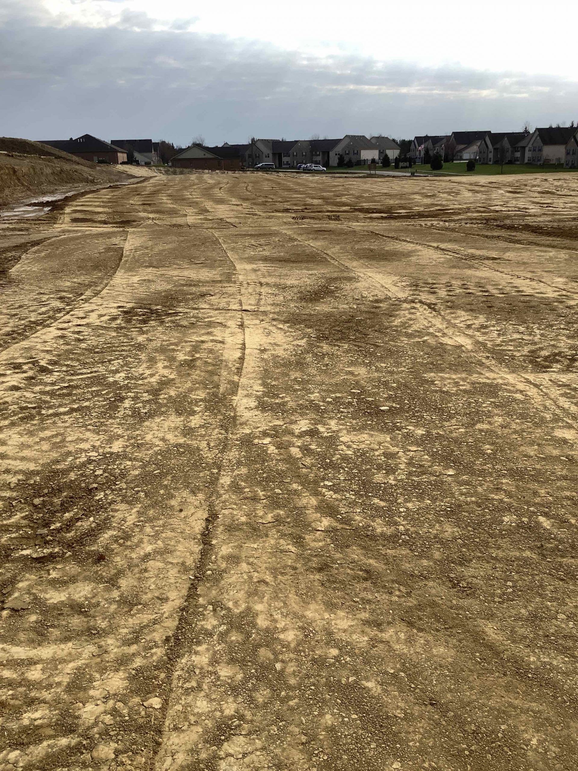 A dirt field with a few houses in the background.