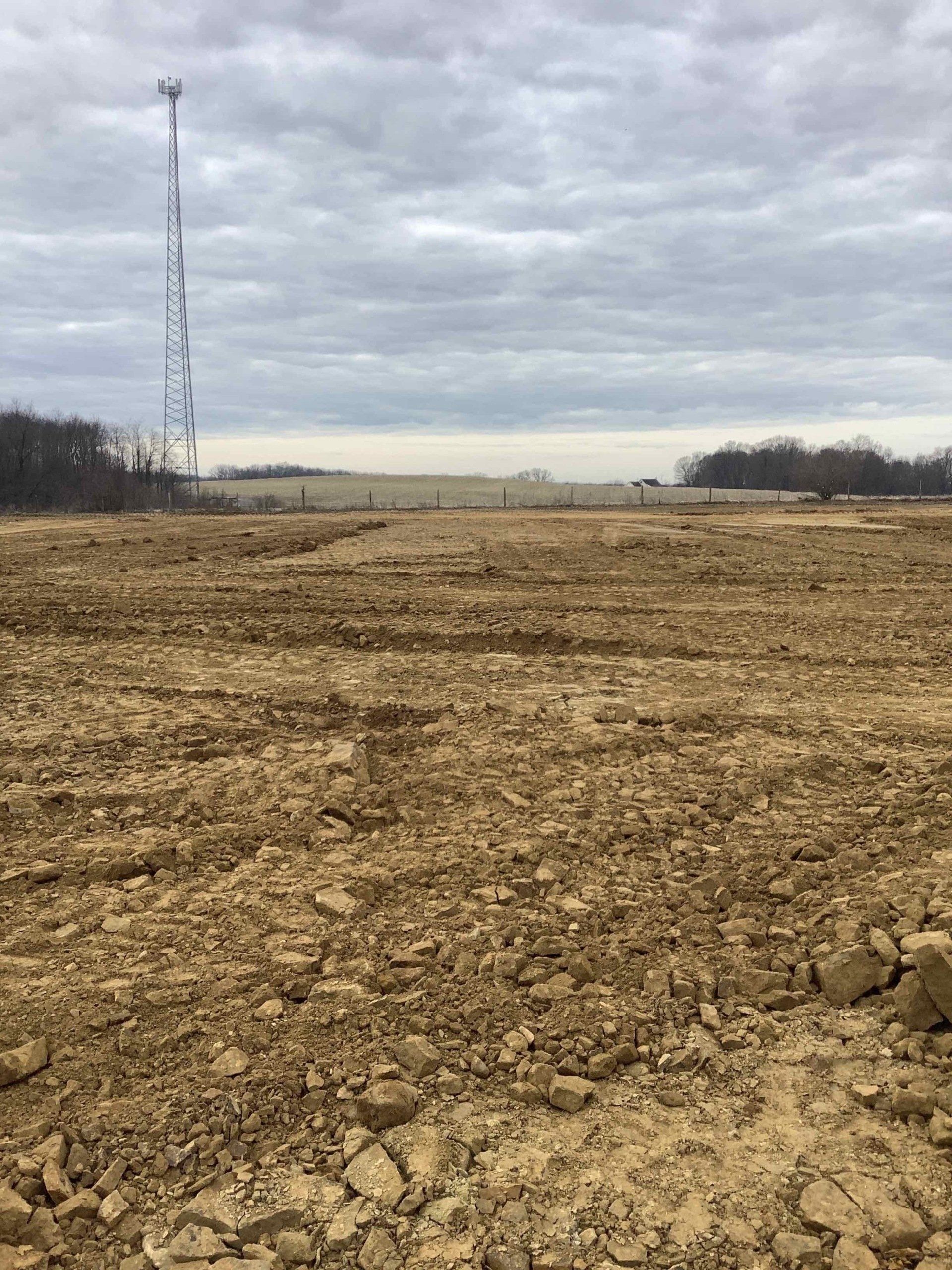 A dirt field with a tower in the background.