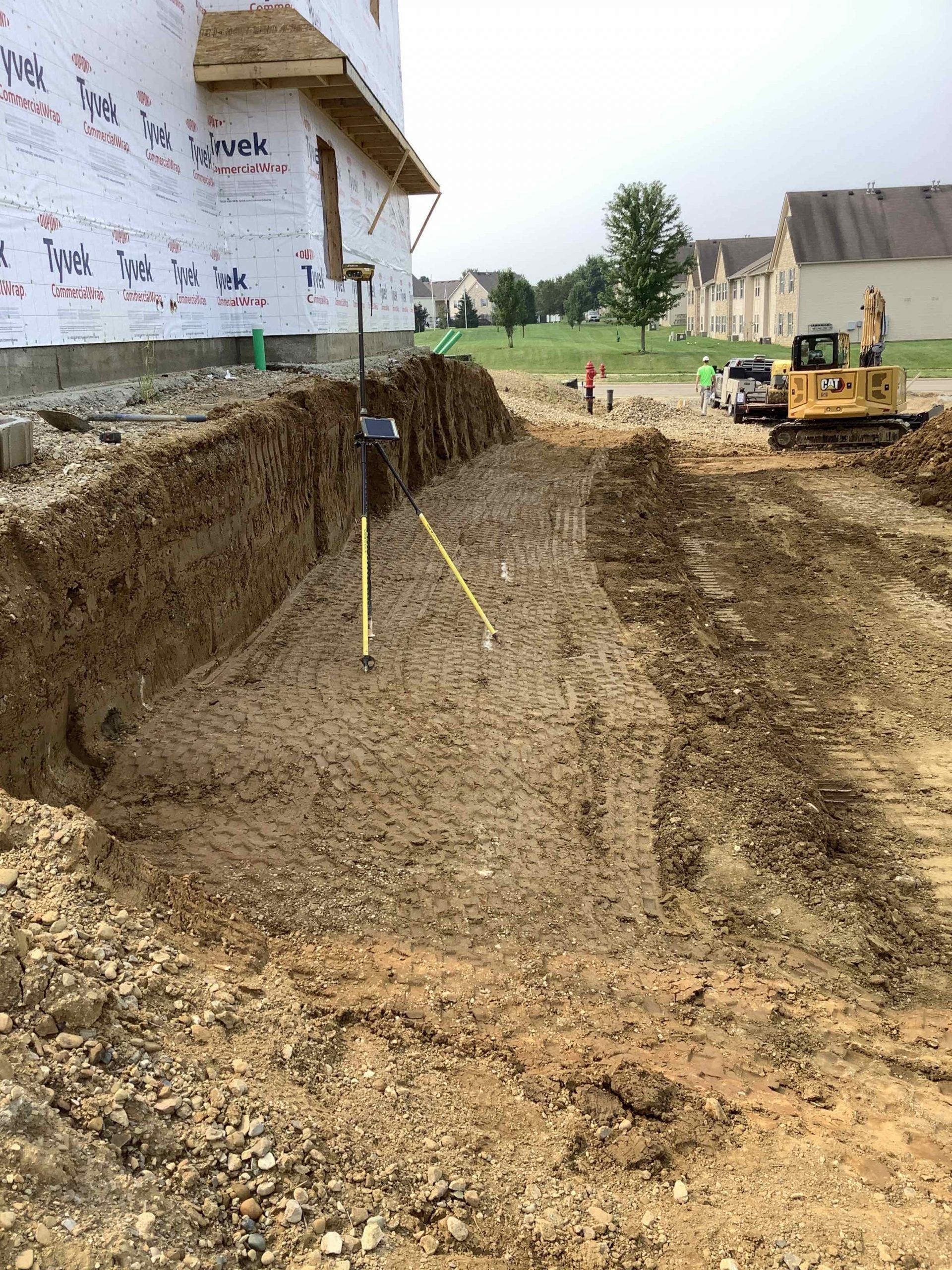 A construction site with a large hole in the ground and a bulldozer in the background.