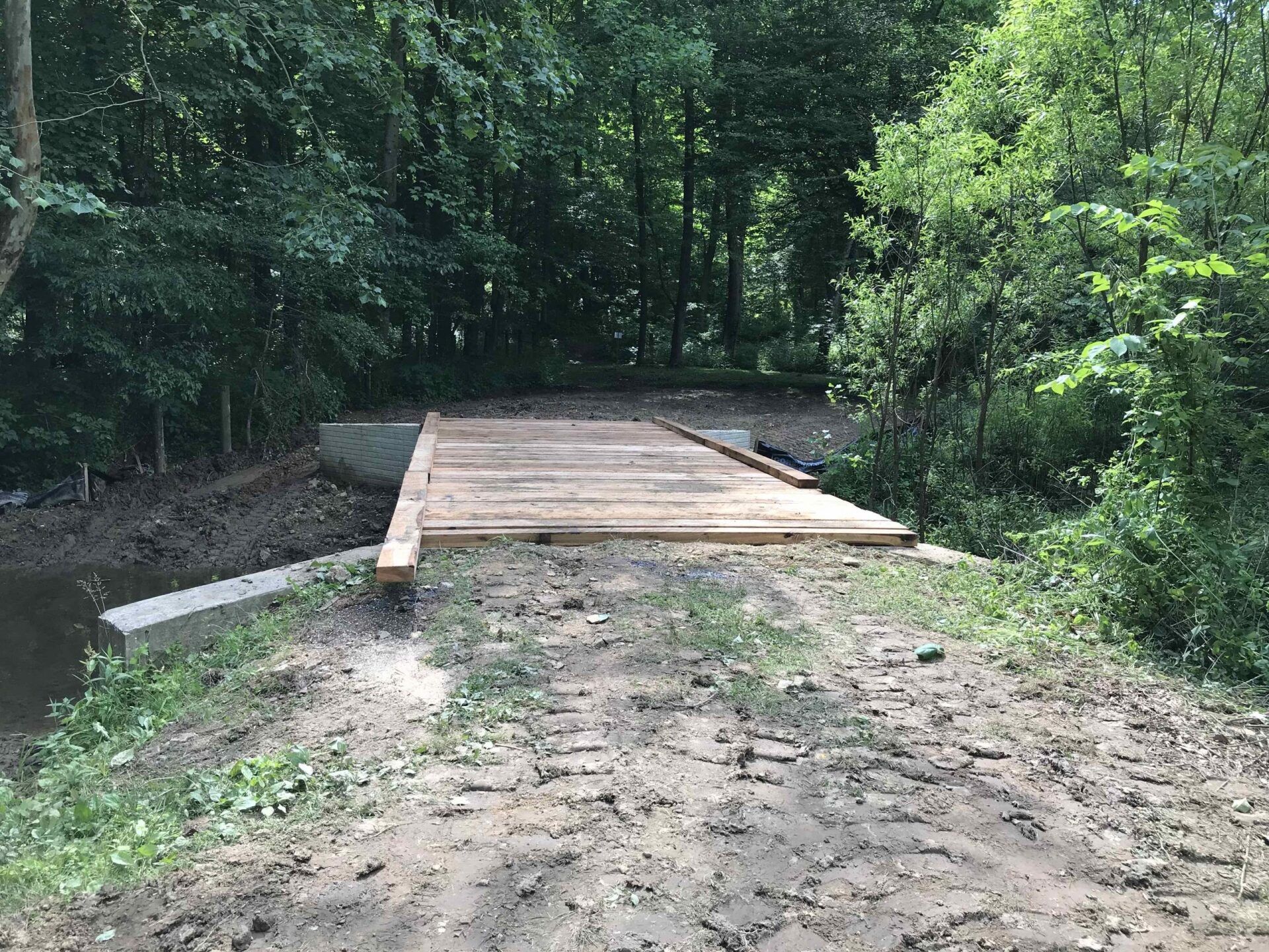 A wooden bridge over a river in the middle of a forest.