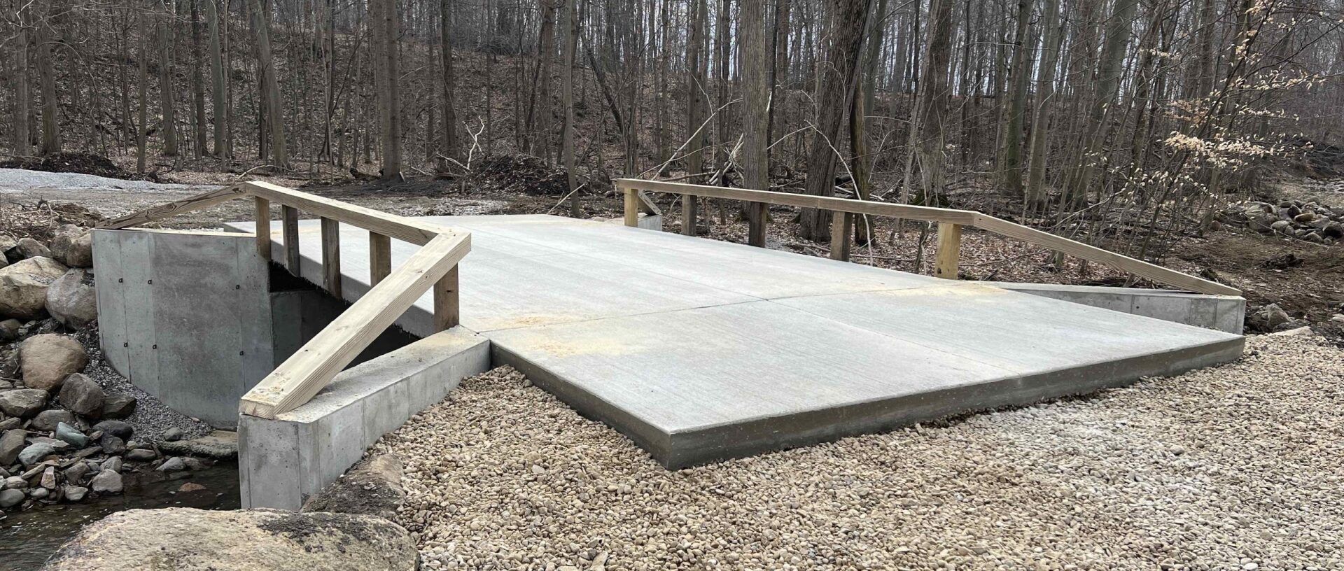 A concrete bridge is being built over a stream in the woods.