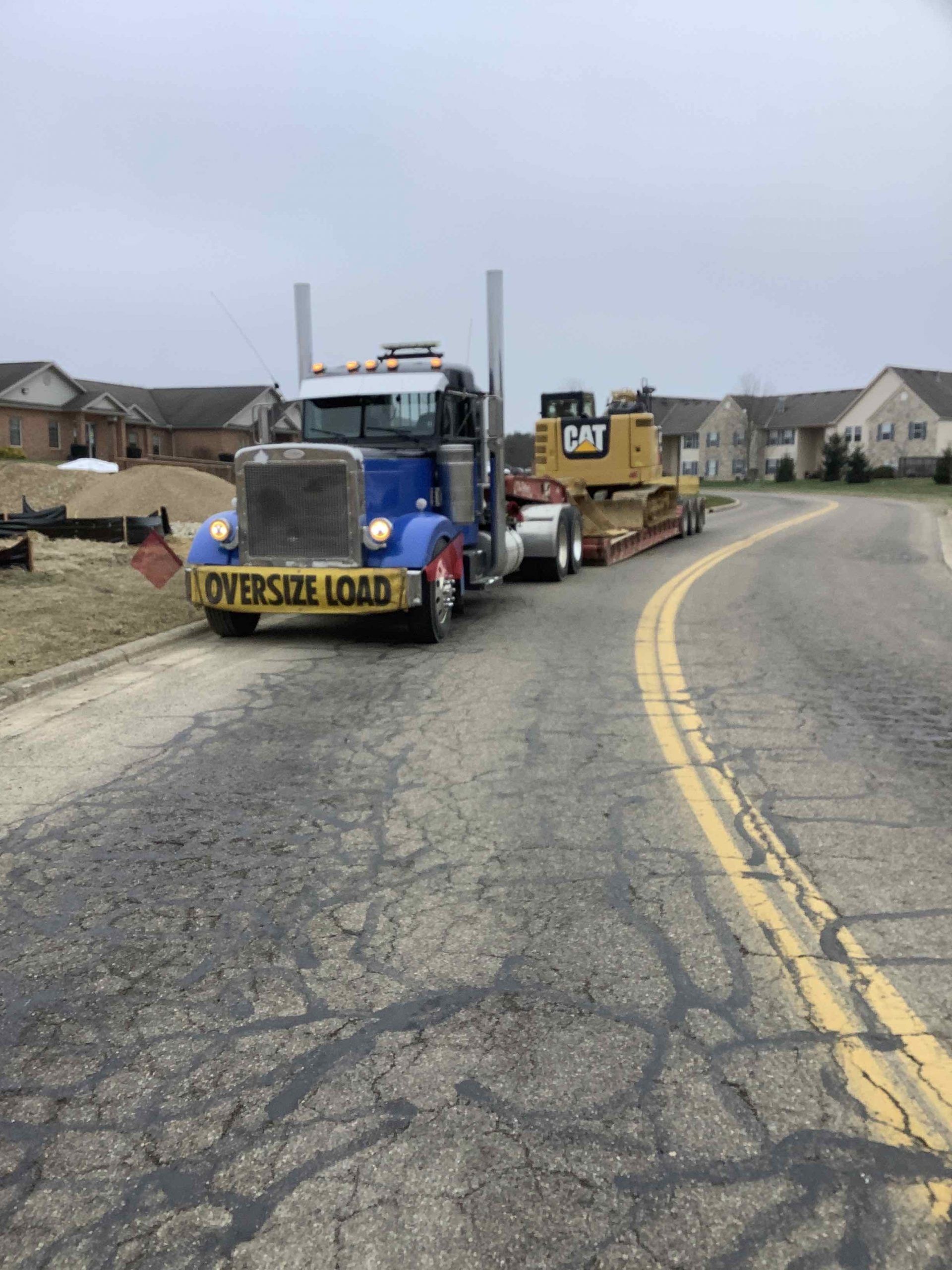 A semi truck is carrying a bulldozer down a road.