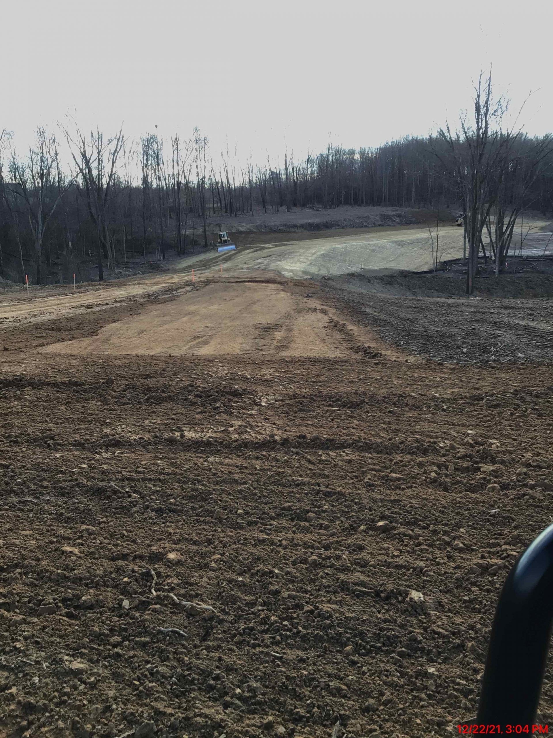 A tractor is plowing a field with trees in the background