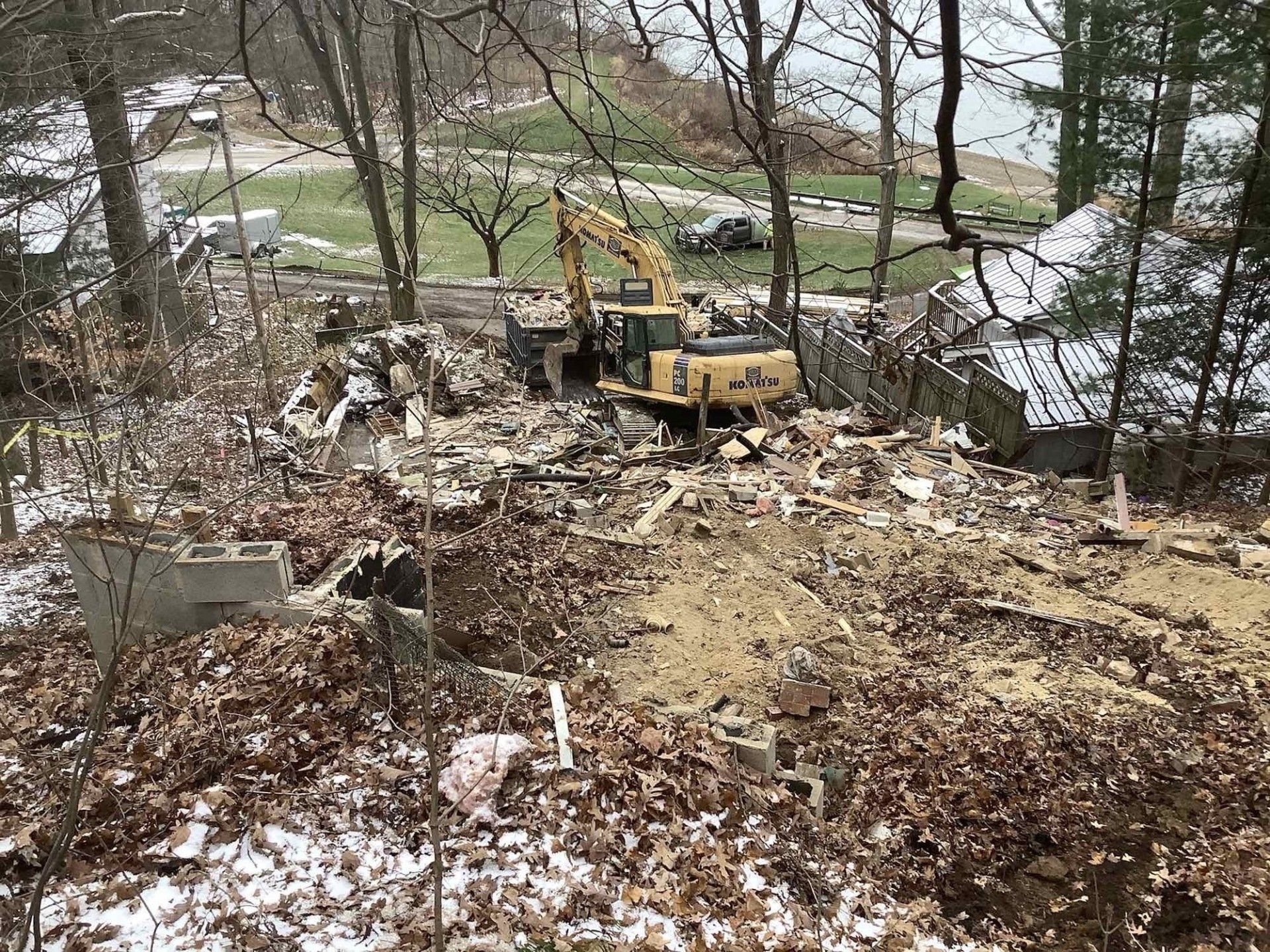 A yellow excavator is sitting in the middle of a pile of leaves.