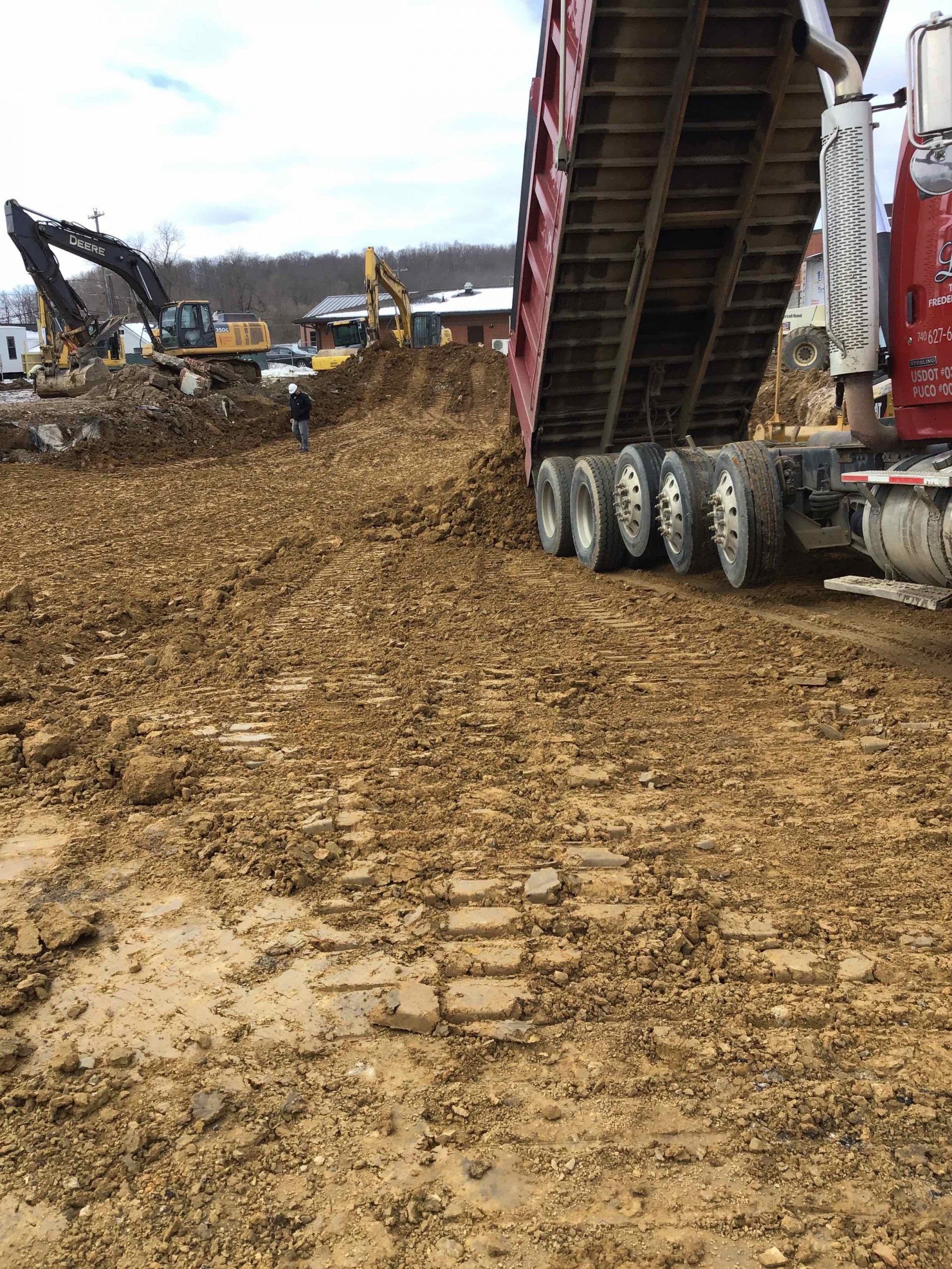 A dump truck is dumping dirt into a construction site.