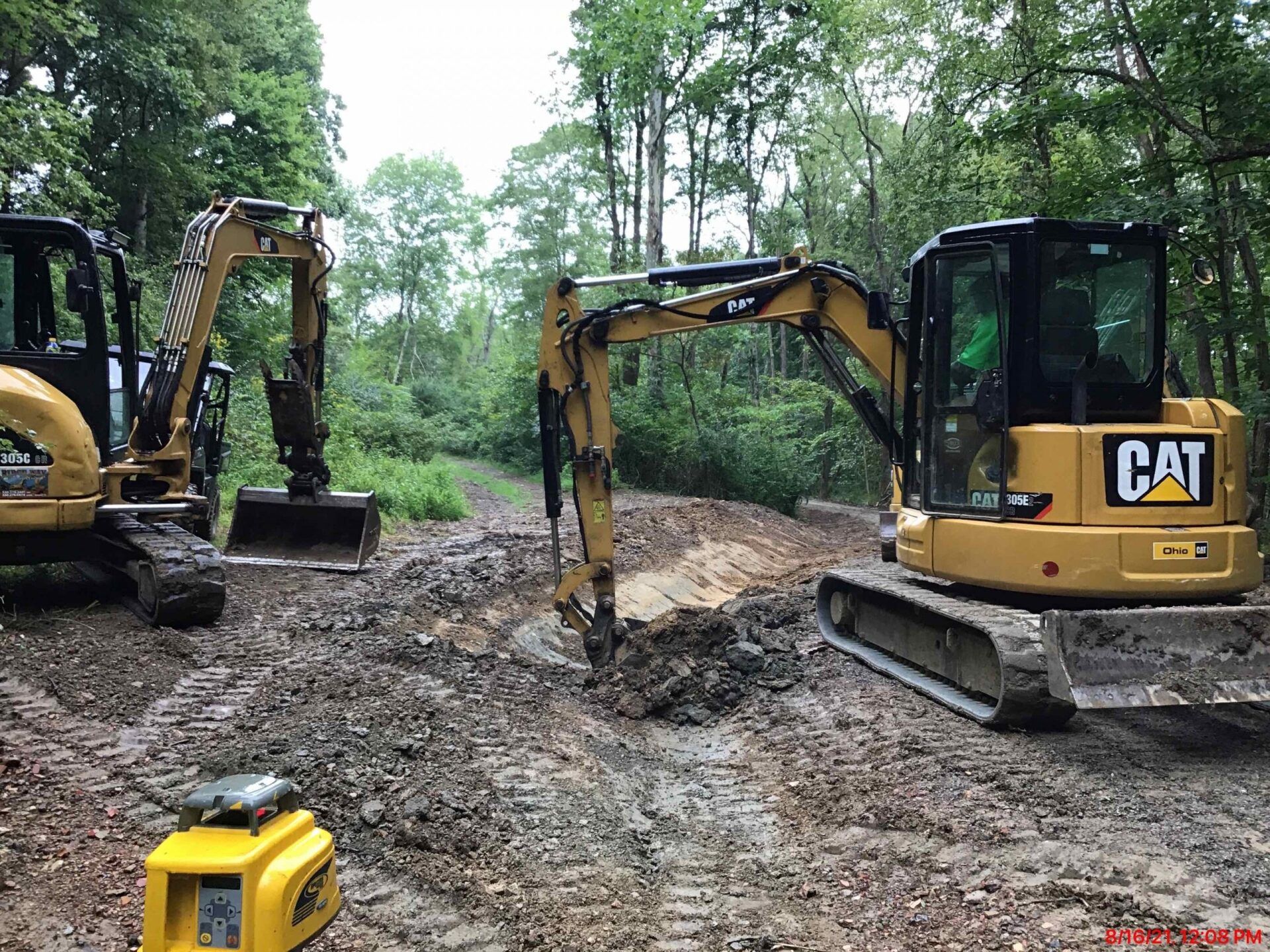 Two cat excavators are digging a hole in the dirt.