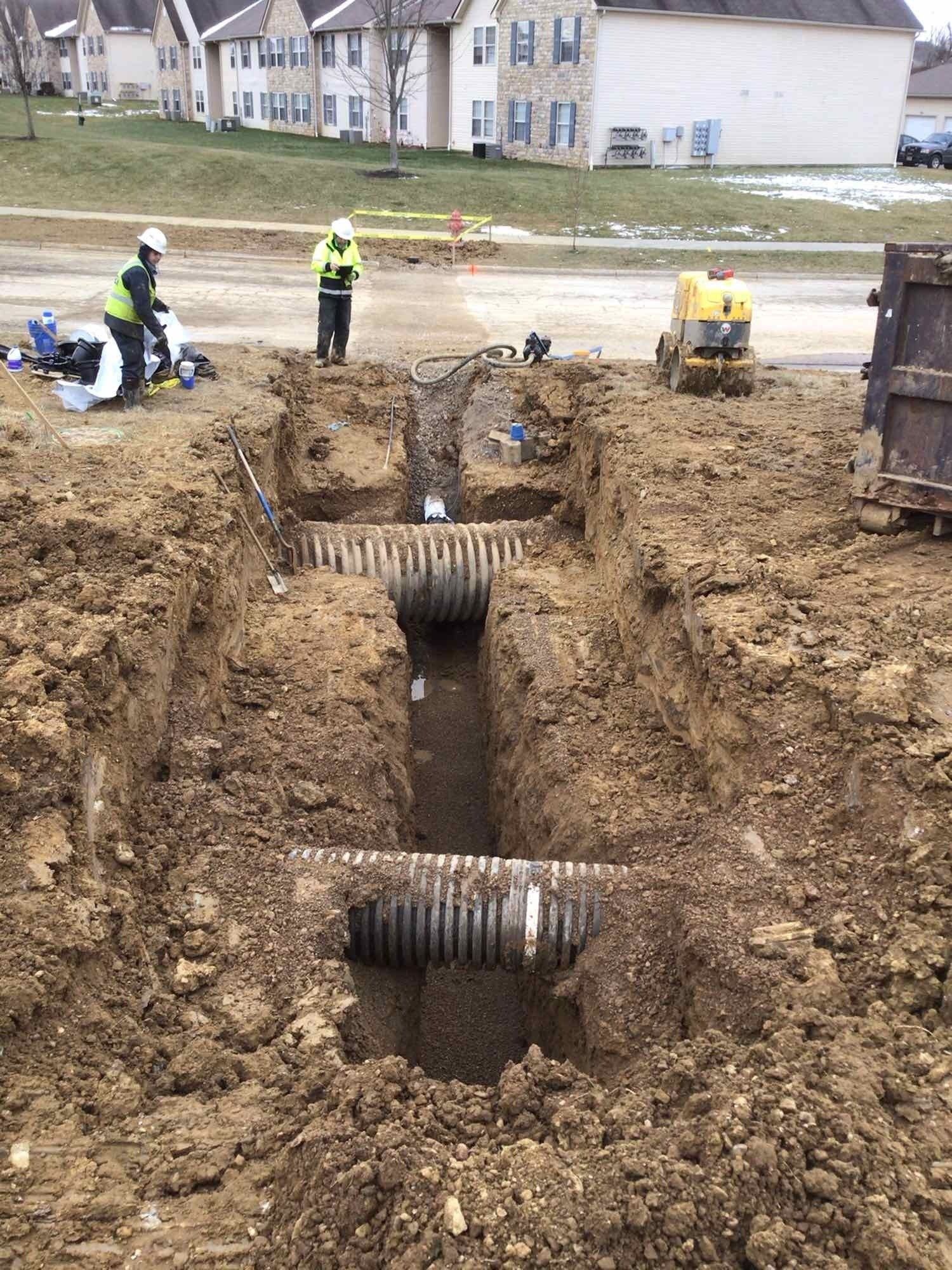 A group of construction workers are digging a trench in the dirt.