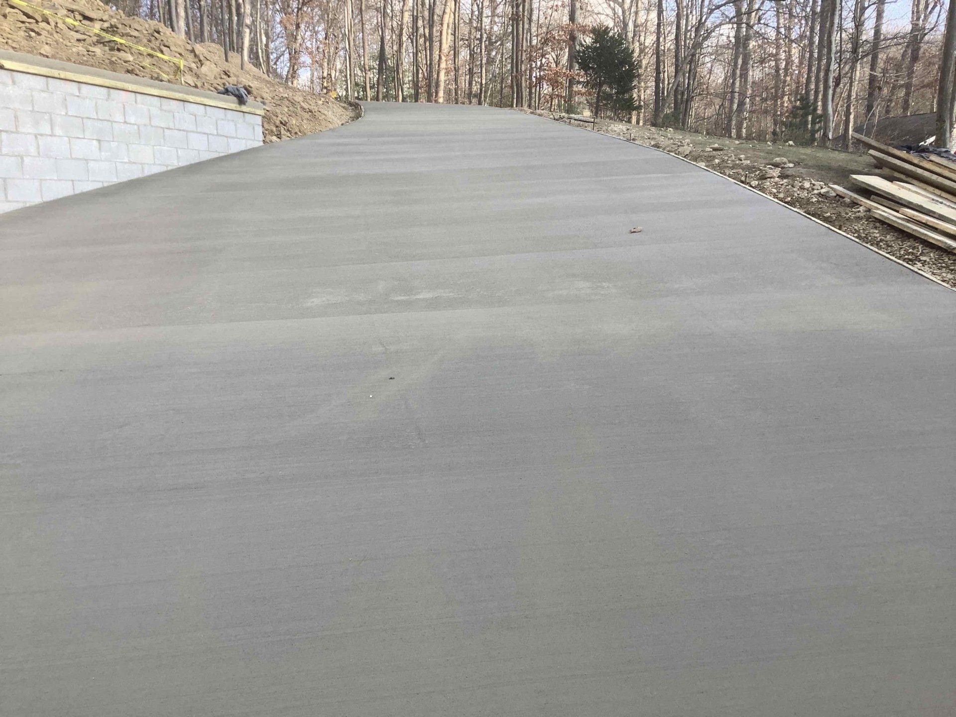 A concrete driveway going up a hill in the woods.
