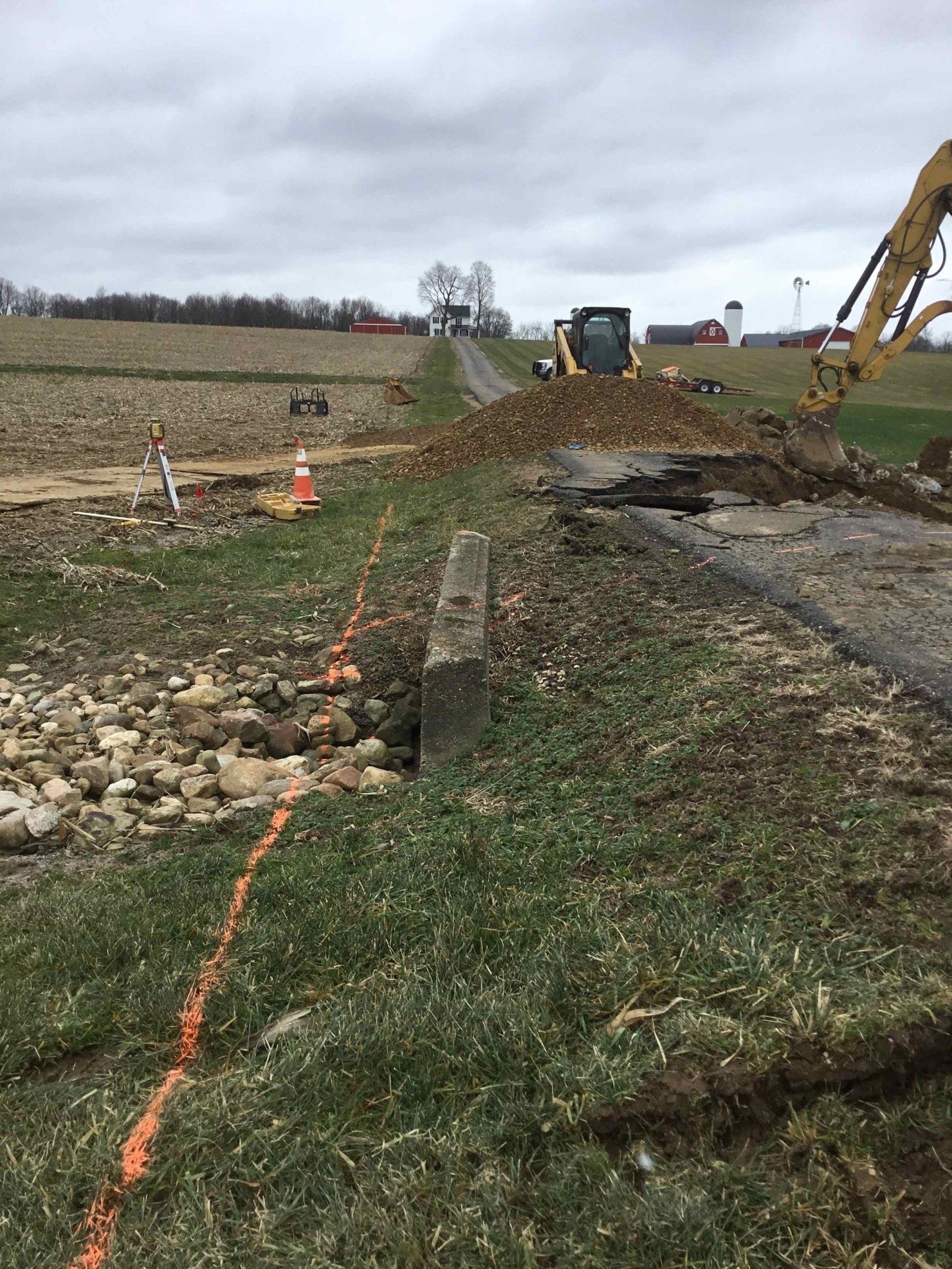 A construction site on the side of a road with a tractor in the background.