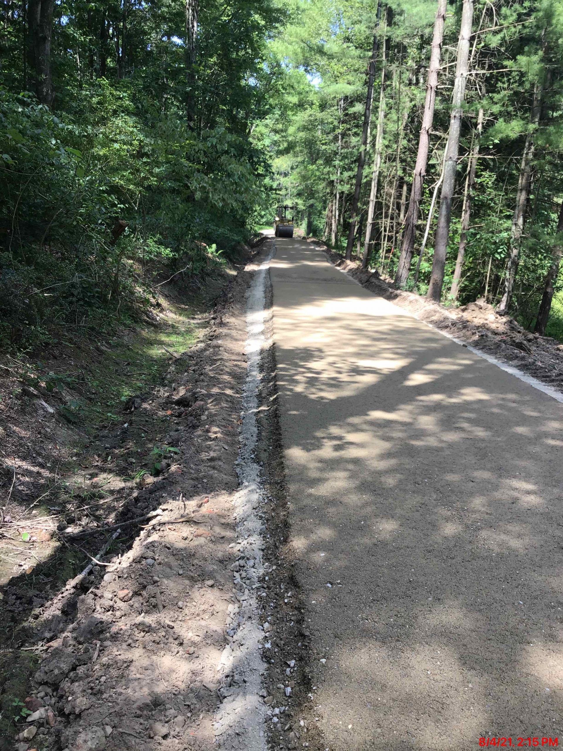 A truck is driving down a dirt road in the woods.
