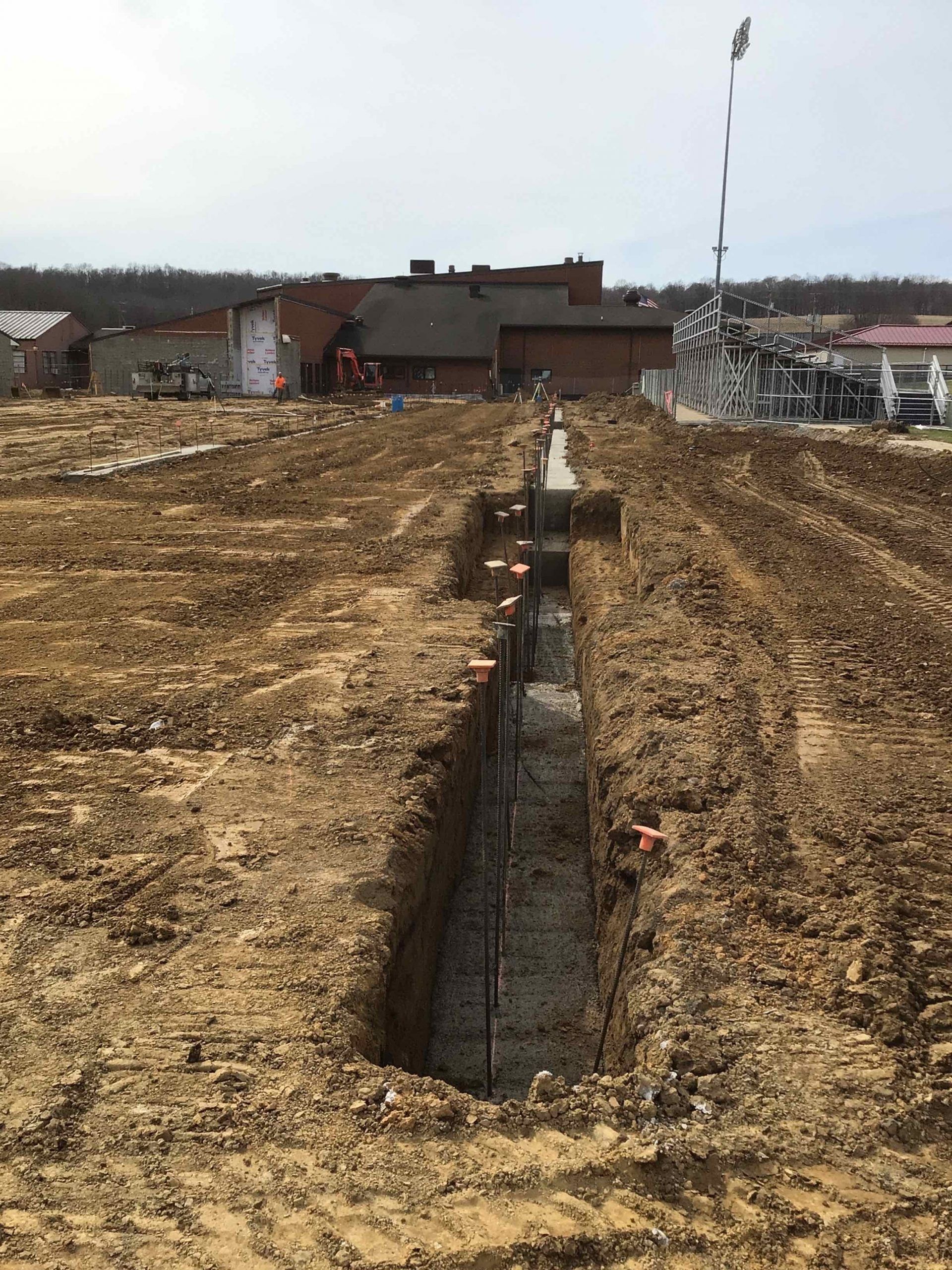 A large dirt field with a brick building in the background.