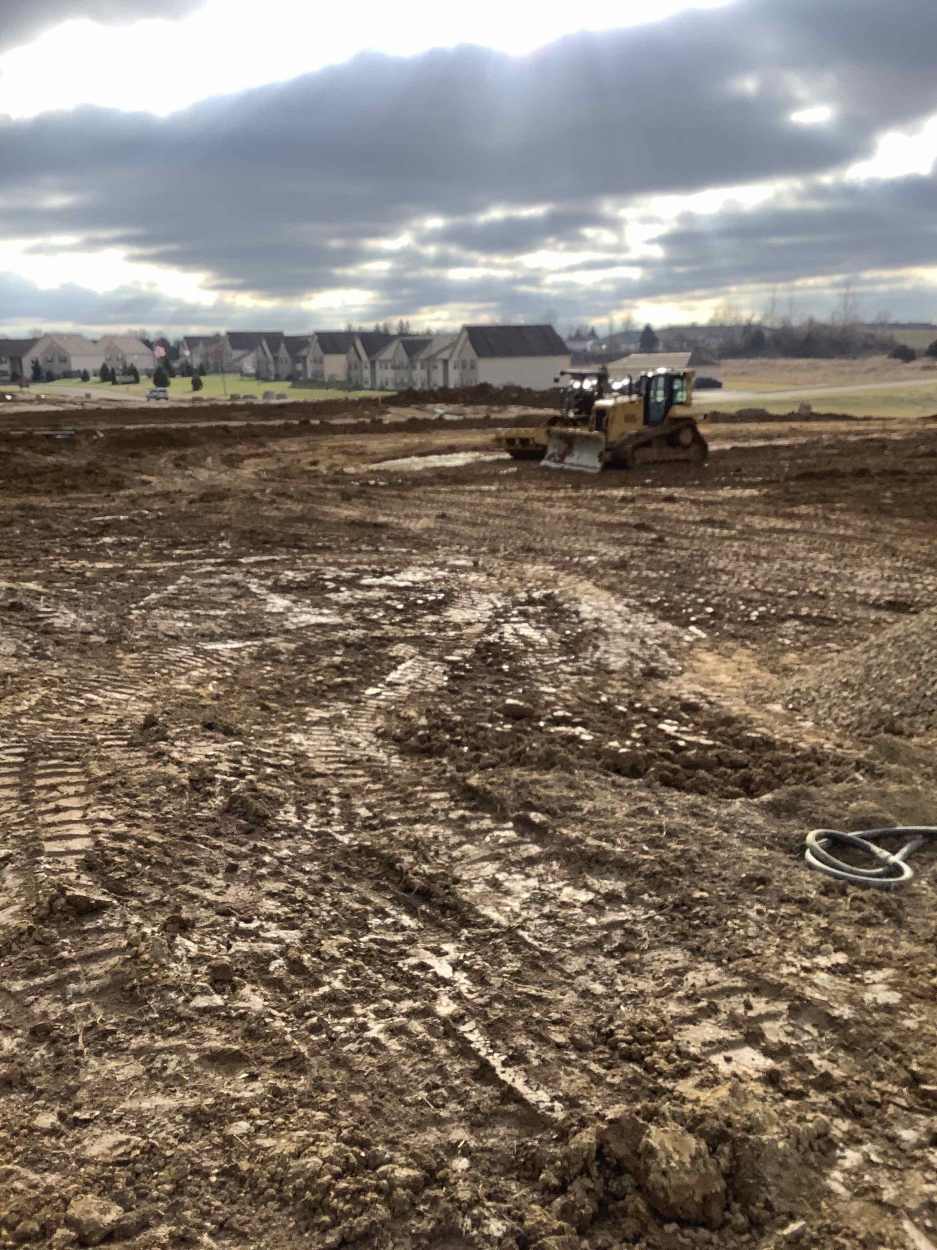 A bulldozer is moving dirt in a muddy field.