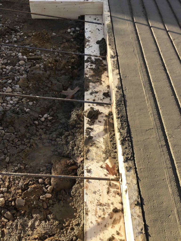 A concrete border is being built next to a wooden deck.