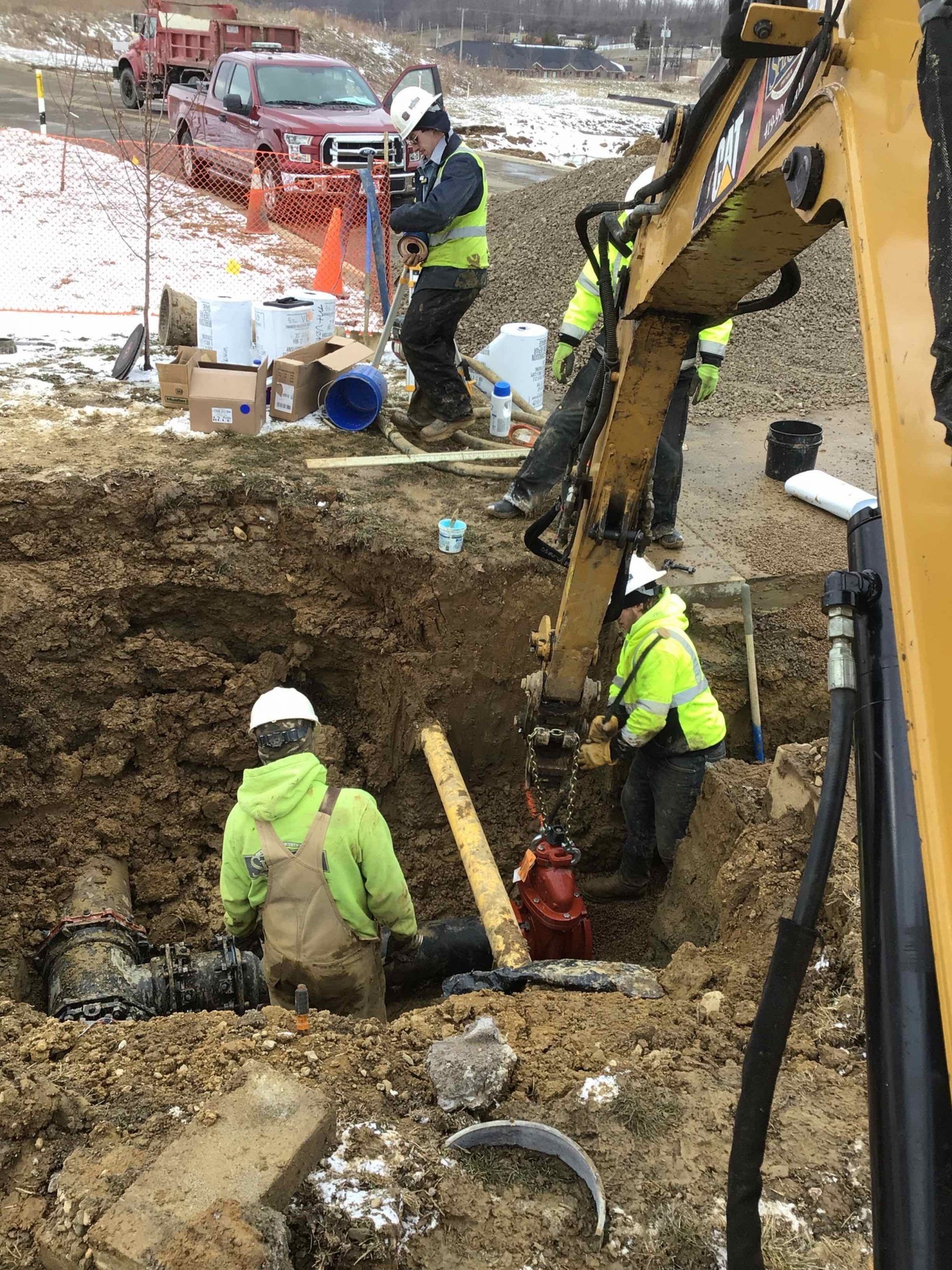 A group of construction workers are digging a hole in the dirt.