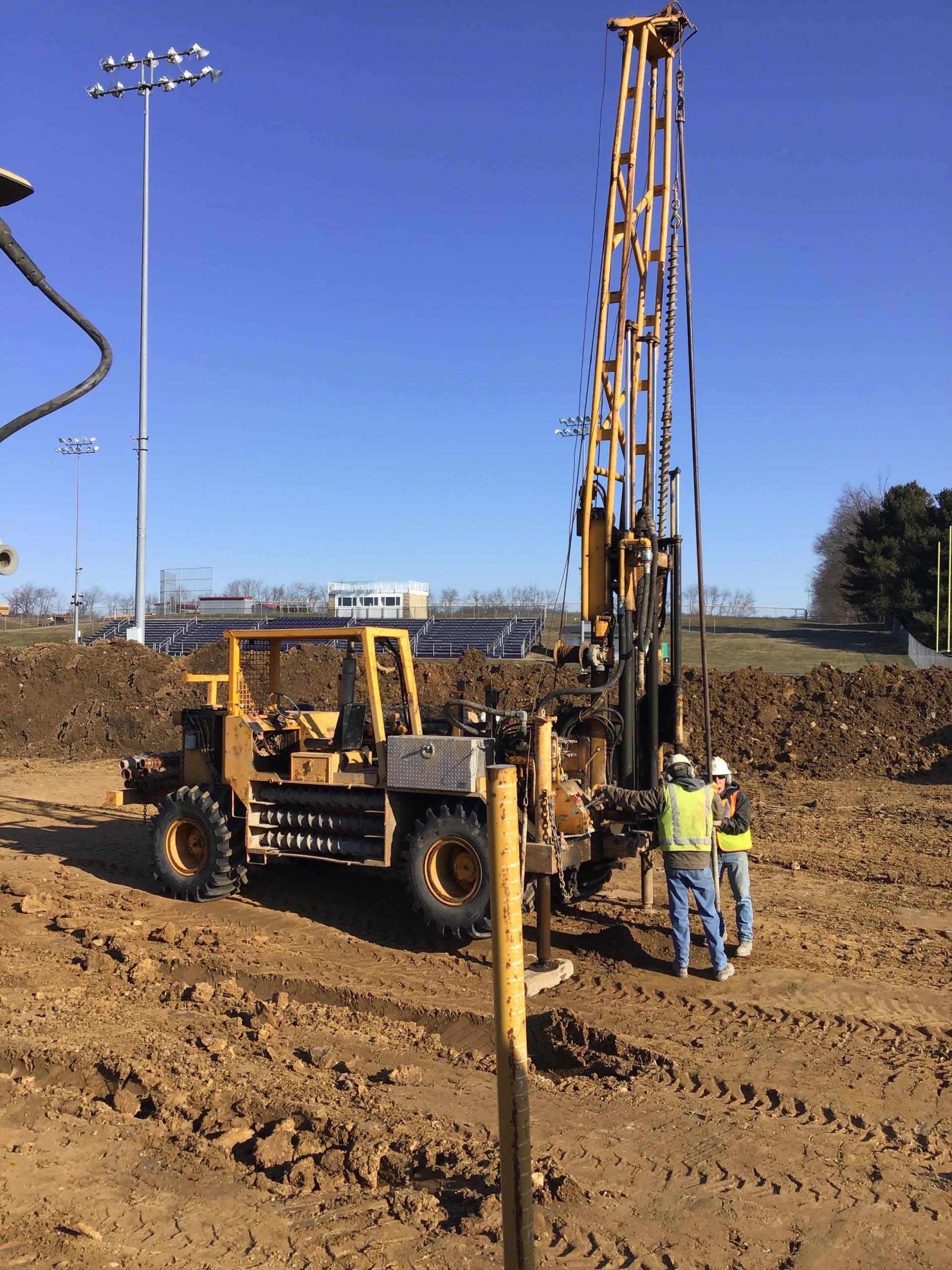 A man is standing next to a machine in the dirt.