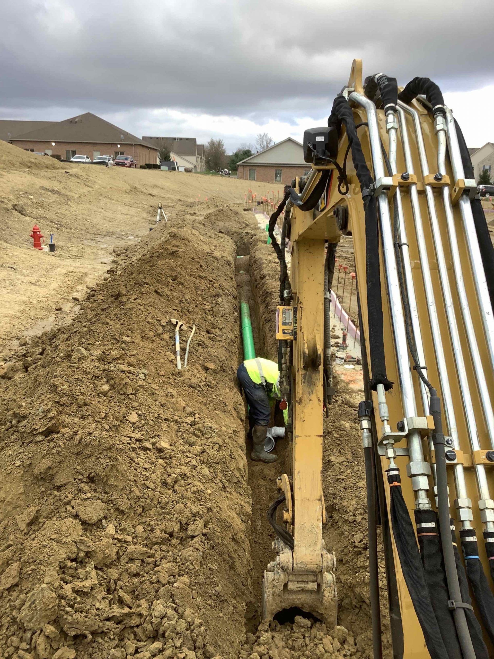 A man is digging a trench with a yellow excavator.