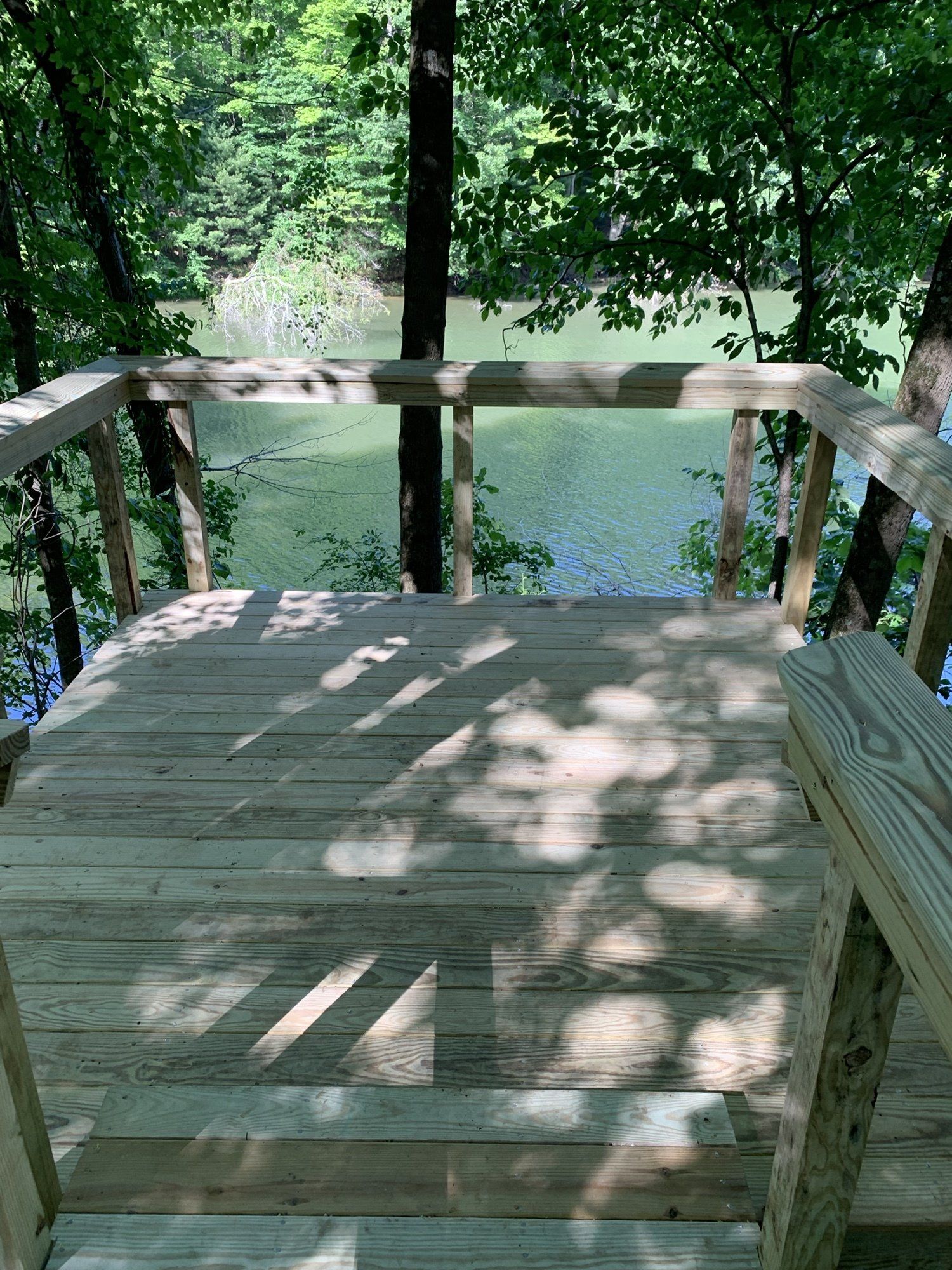 A wooden deck overlooking a lake in the woods.