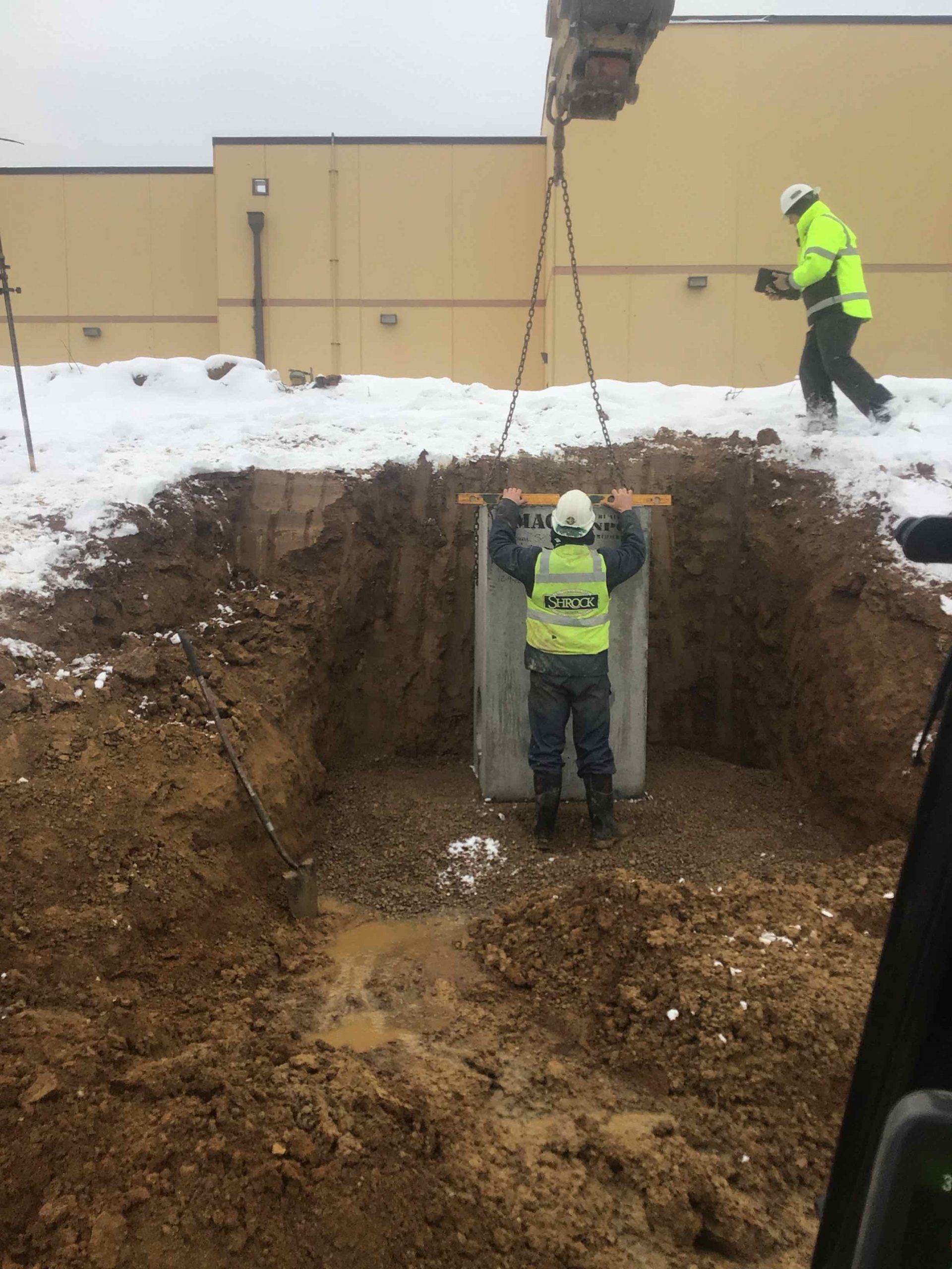 A man is standing in a hole in the ground holding a piece of concrete.