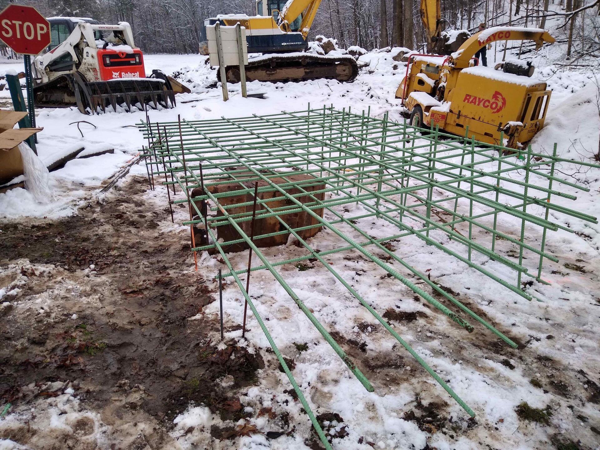 A stop sign is sitting in the snow next to a construction site.