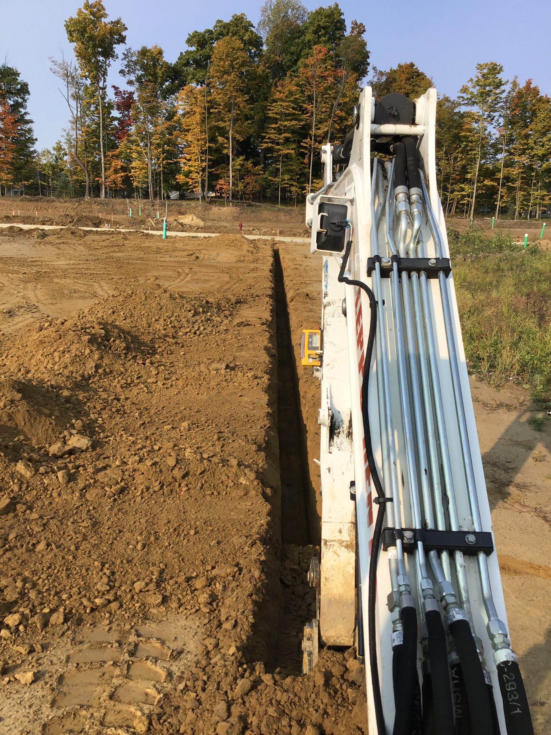 A machine is digging a trench in the dirt in a field.
